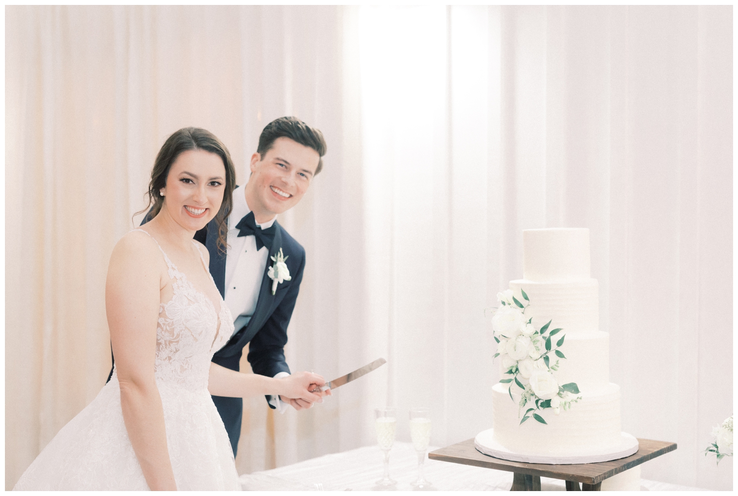bride and groom cutting all white wedding cake