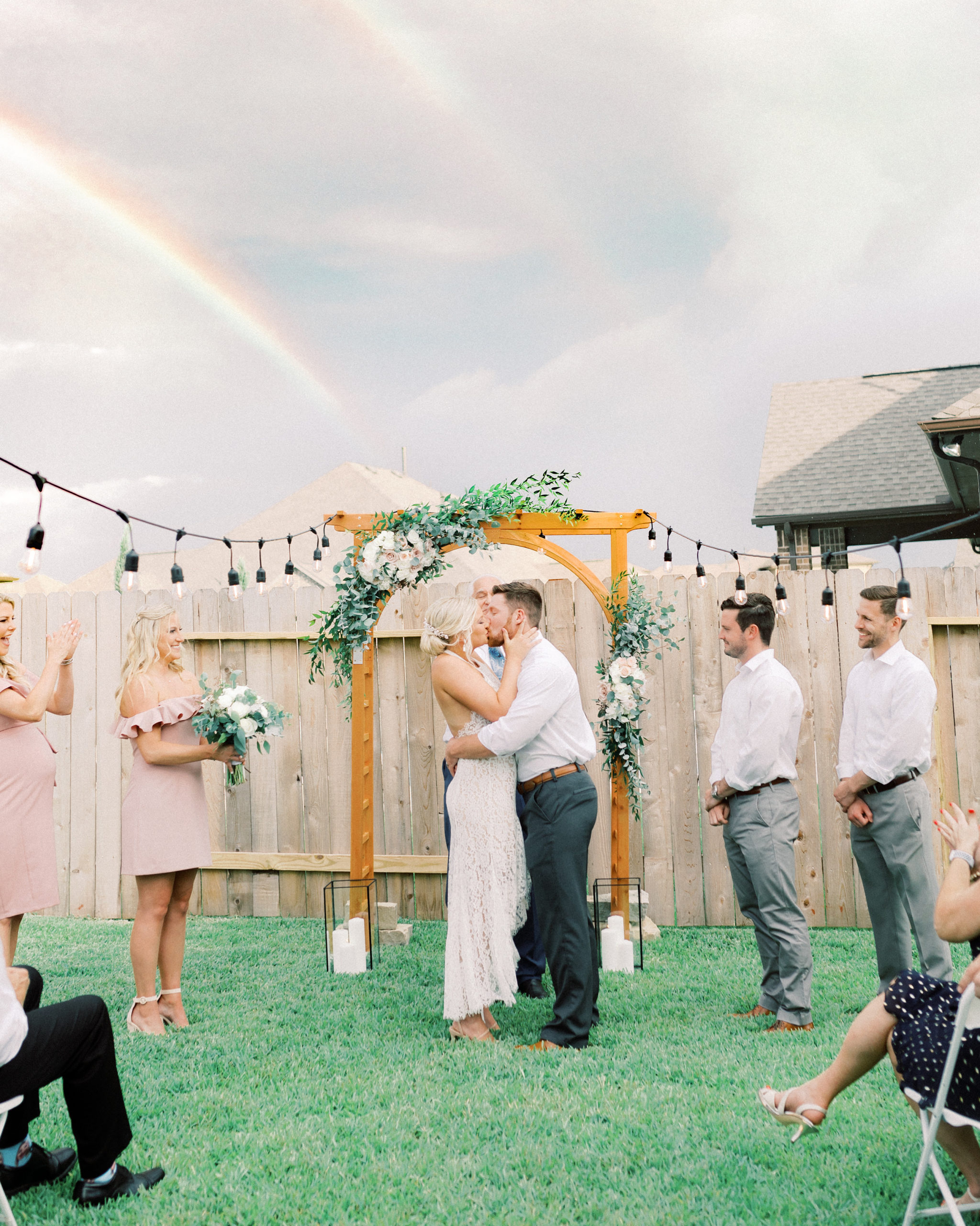 Married couple kissing under a double rainbow