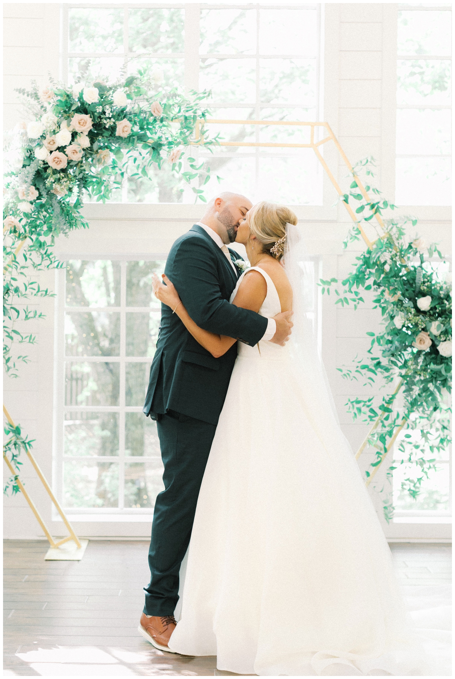 bride-and-groom-kissing-in-front-of-floral-arch