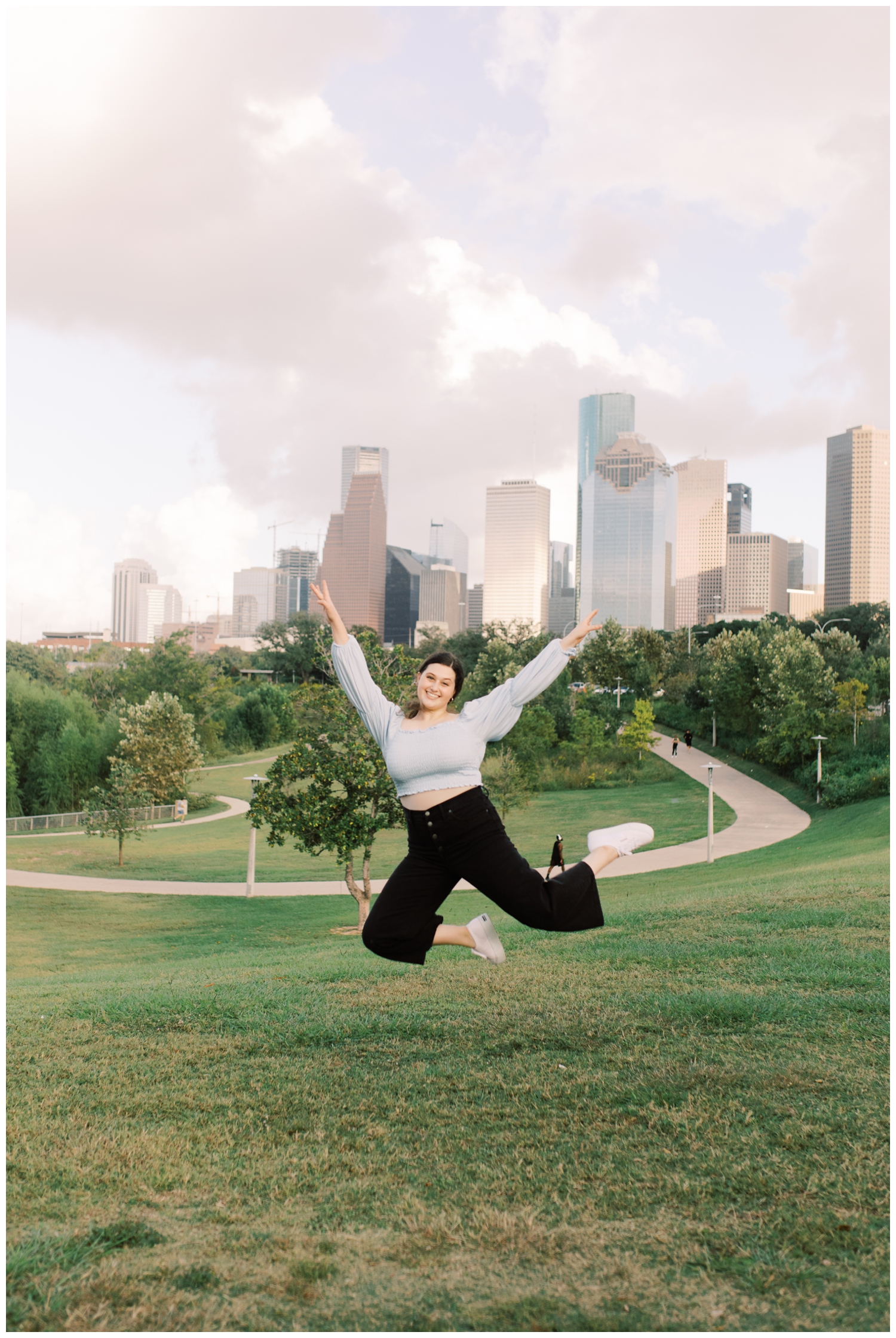 girl jumping with Houston skyline at Buffalo Bayou Park with Reed Gallagher Photography