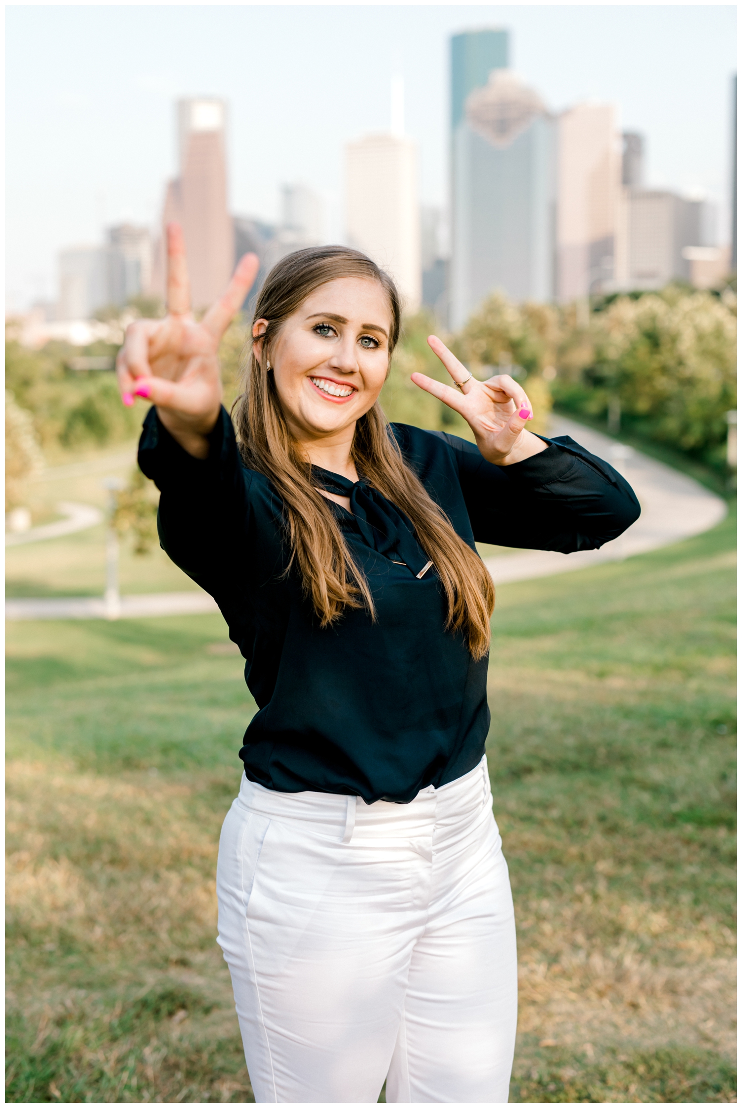 senior girl with peace signs in front of Houston Skyline