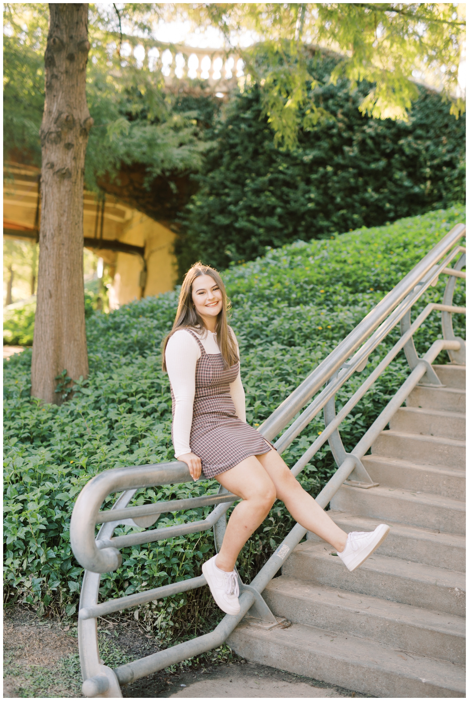 girl kicking while sitting on a rail in downtown Houston for her senior photography session