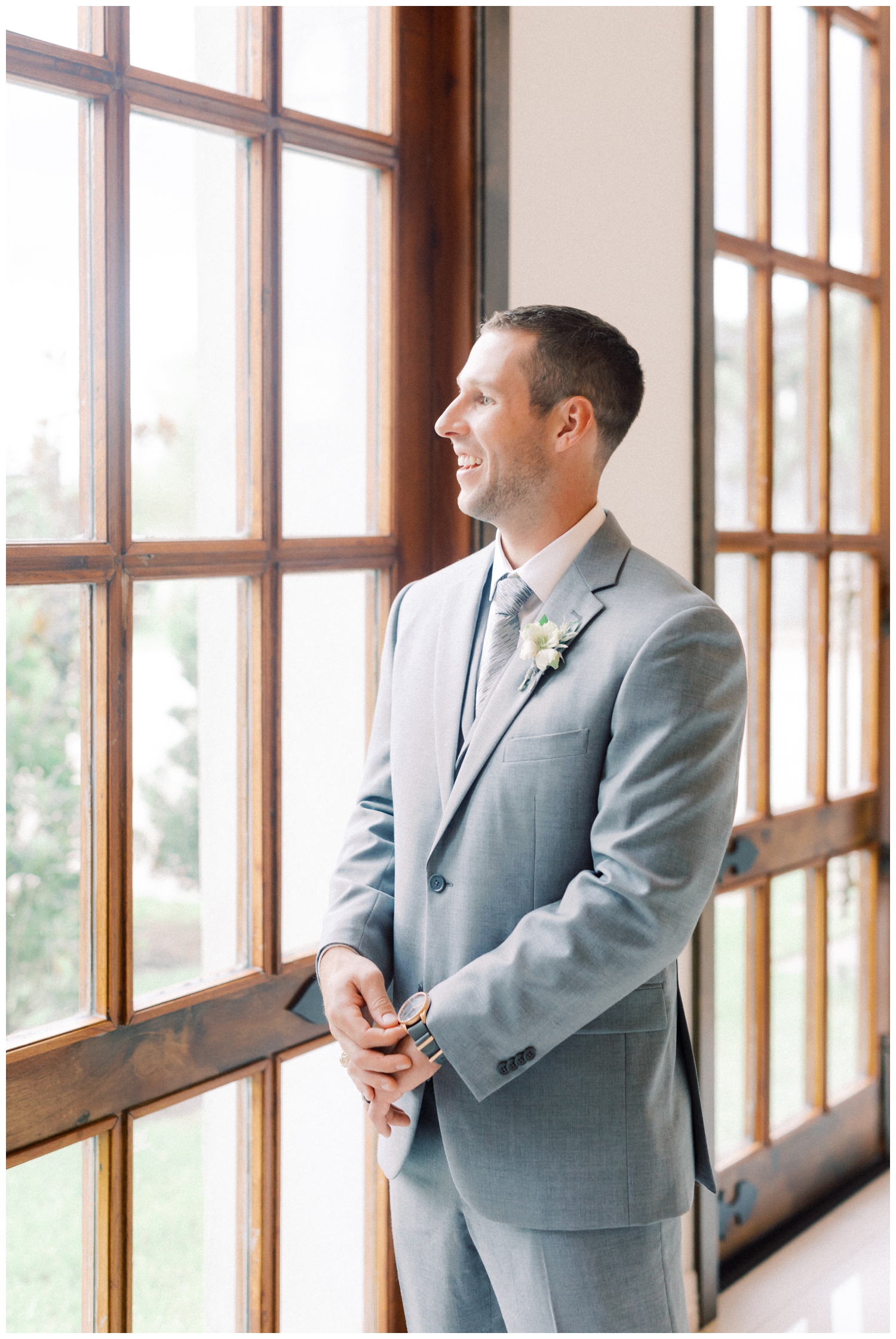 groom looking out a window at wedding venue in Houston