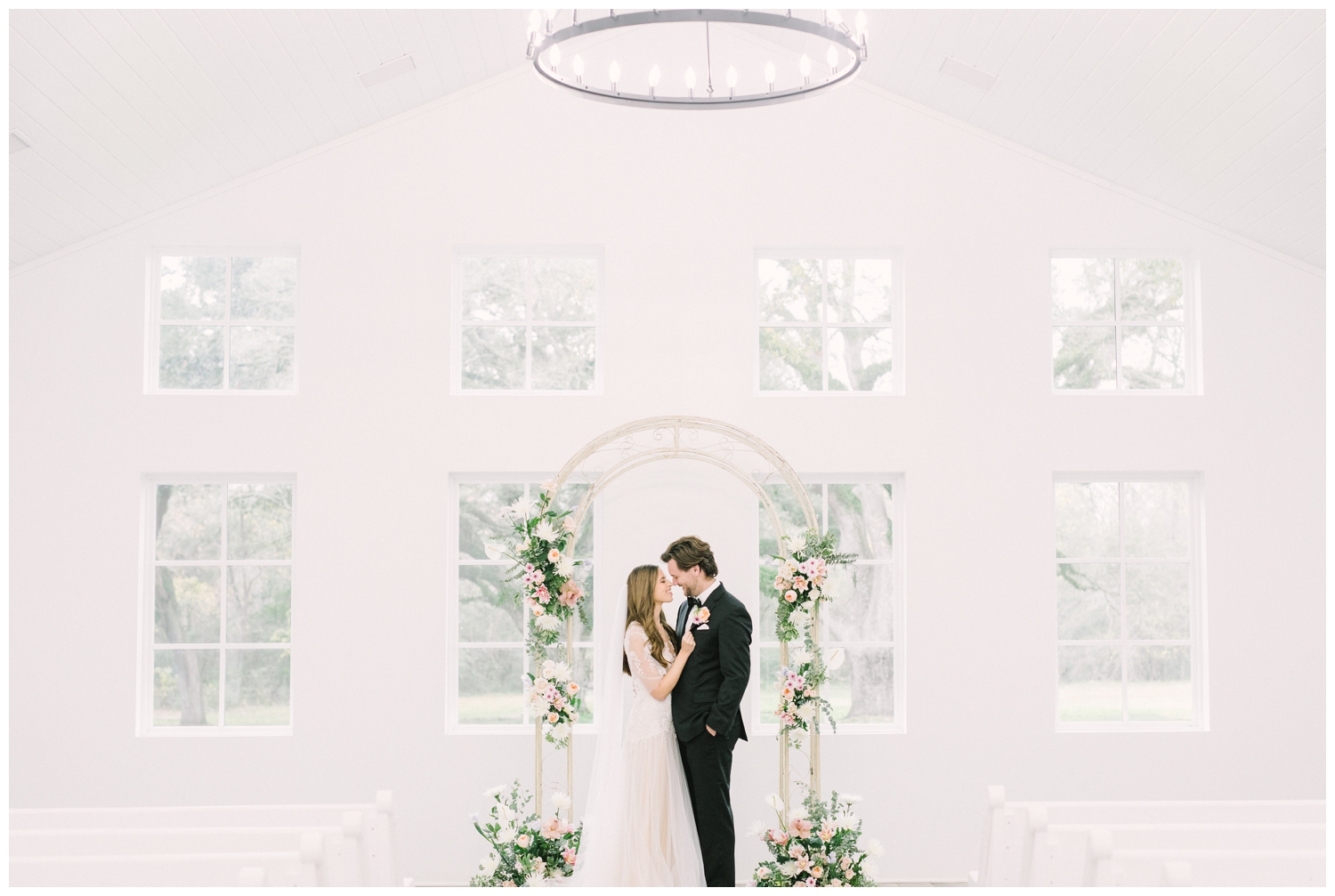 natural light chapel at Addison Woods wedding venue with bride and groom under a floral arch