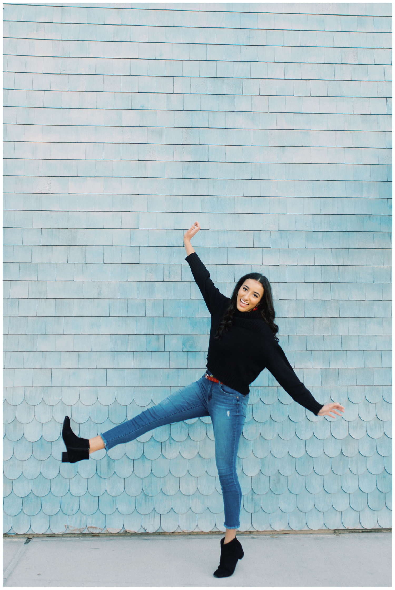 high school senior posing with kicking at blue wall in Houston, Texas
