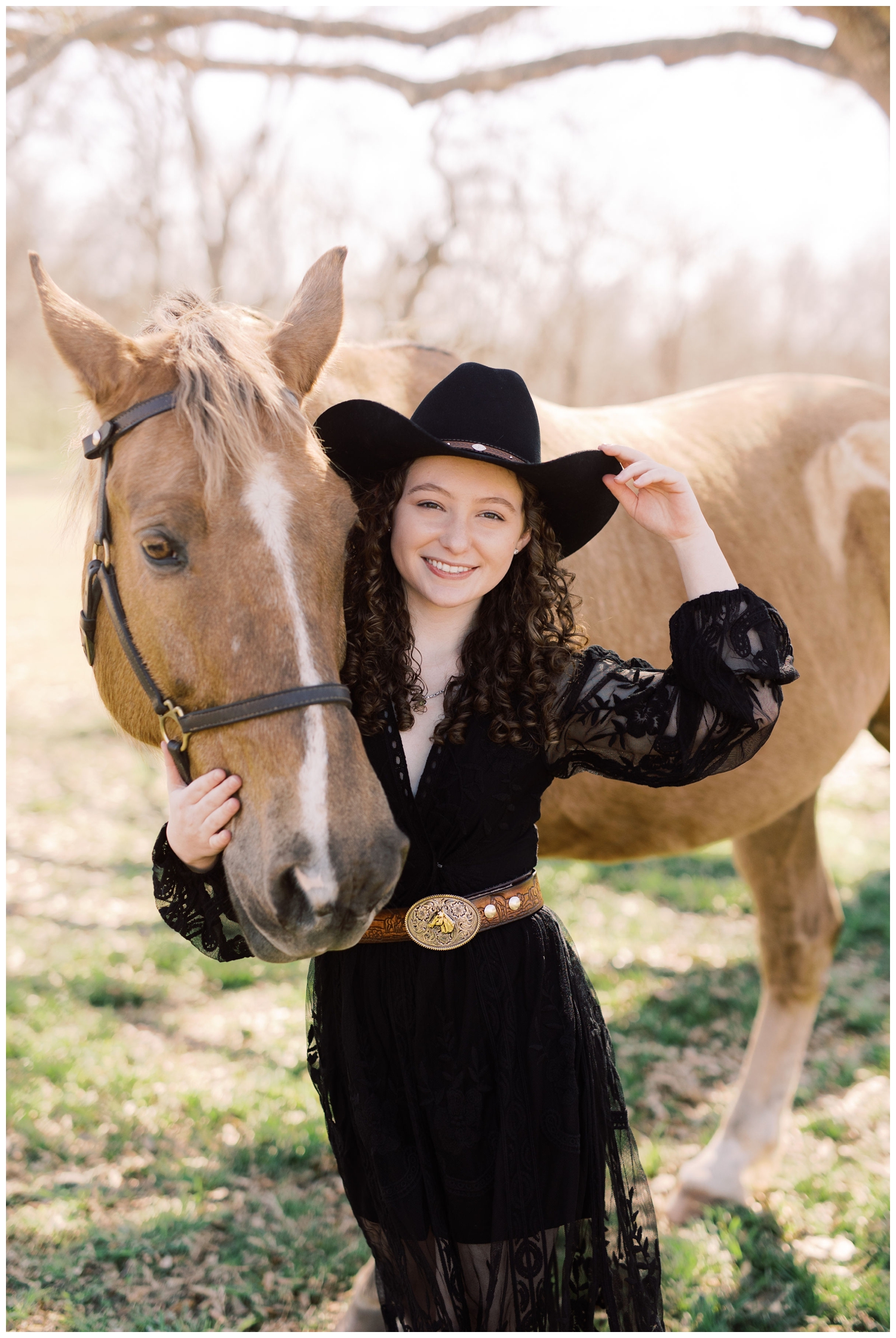 senior girl tipping hat while hugging a horse during a Cypress senior session