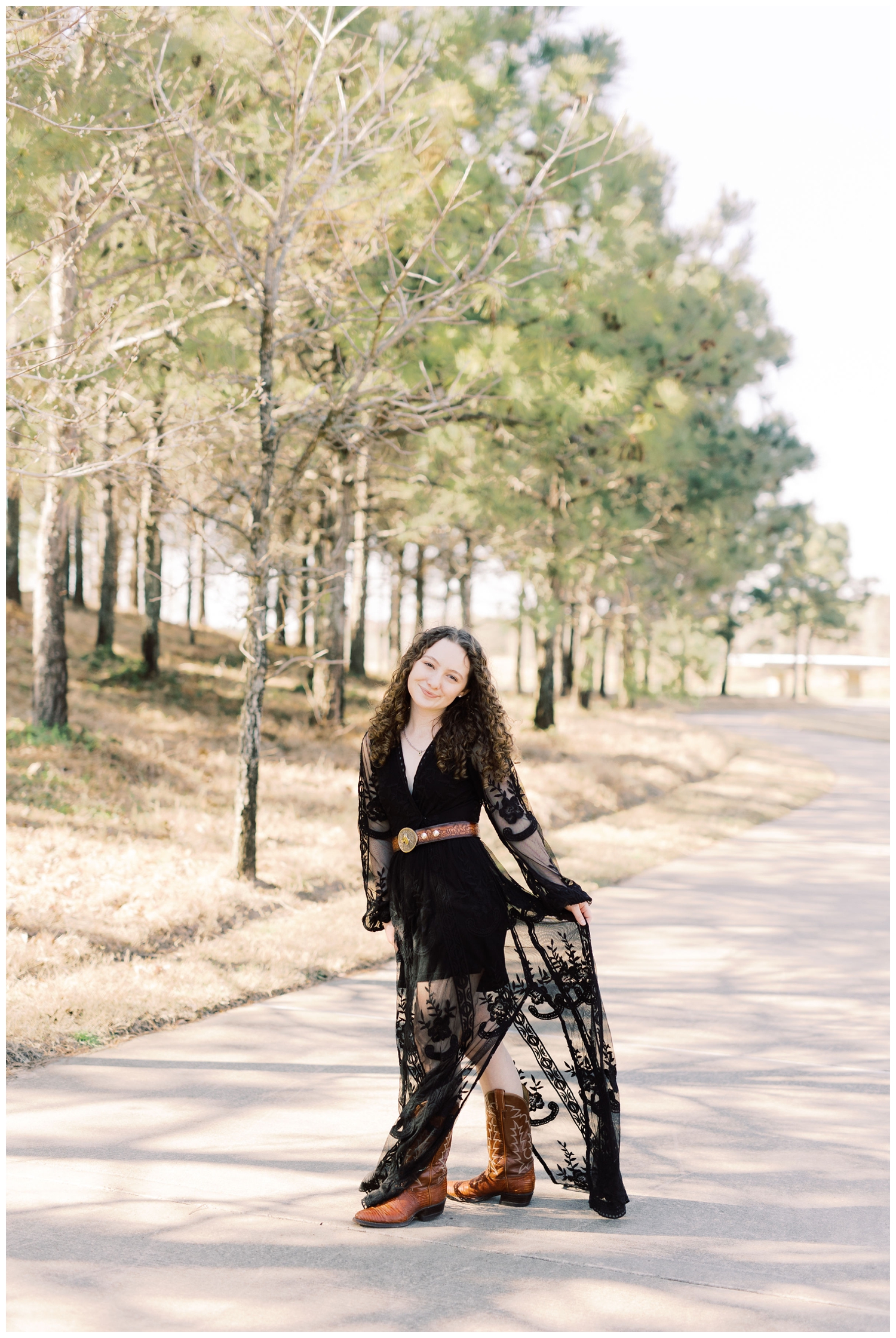 girl holding long black dress standing on sidewalk for Cypress Senior Session