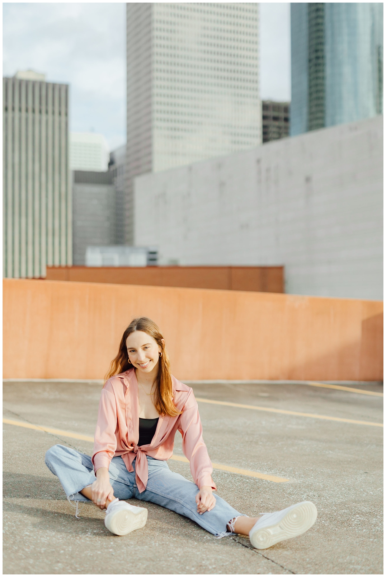 girl sitting on ground in front of downtown Houston skyline