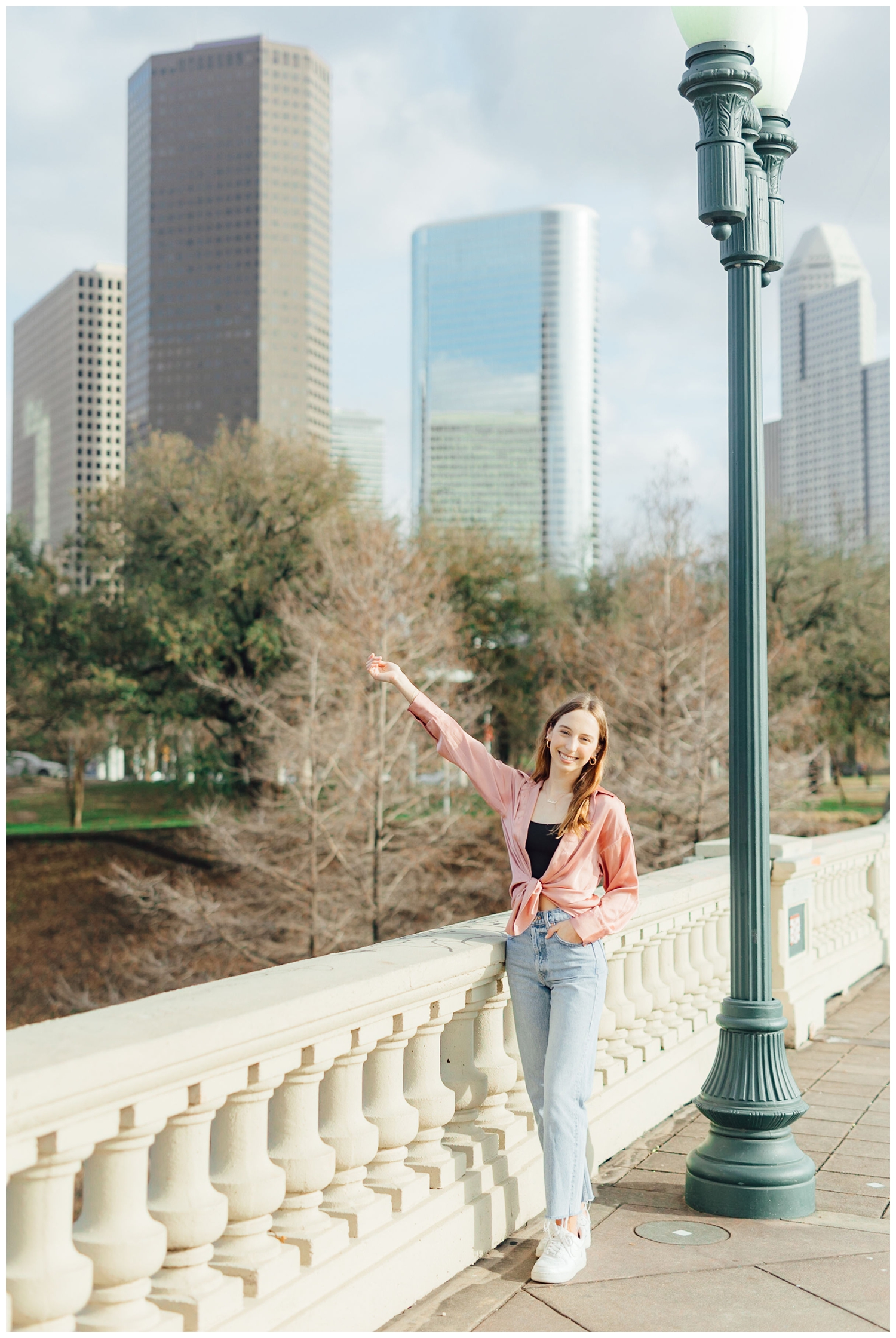 girl standing with arm out in front of downtown Houston skyline