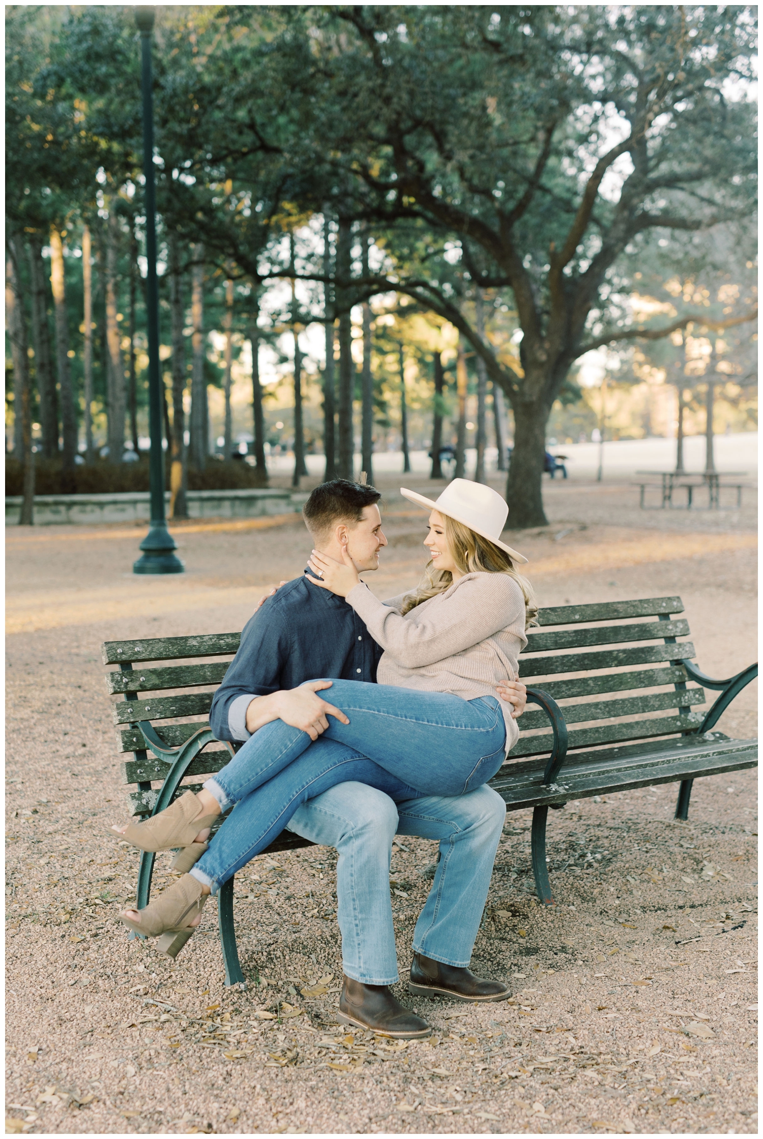 engaged couple laying on park bench at Hermann Park in Houston Texas