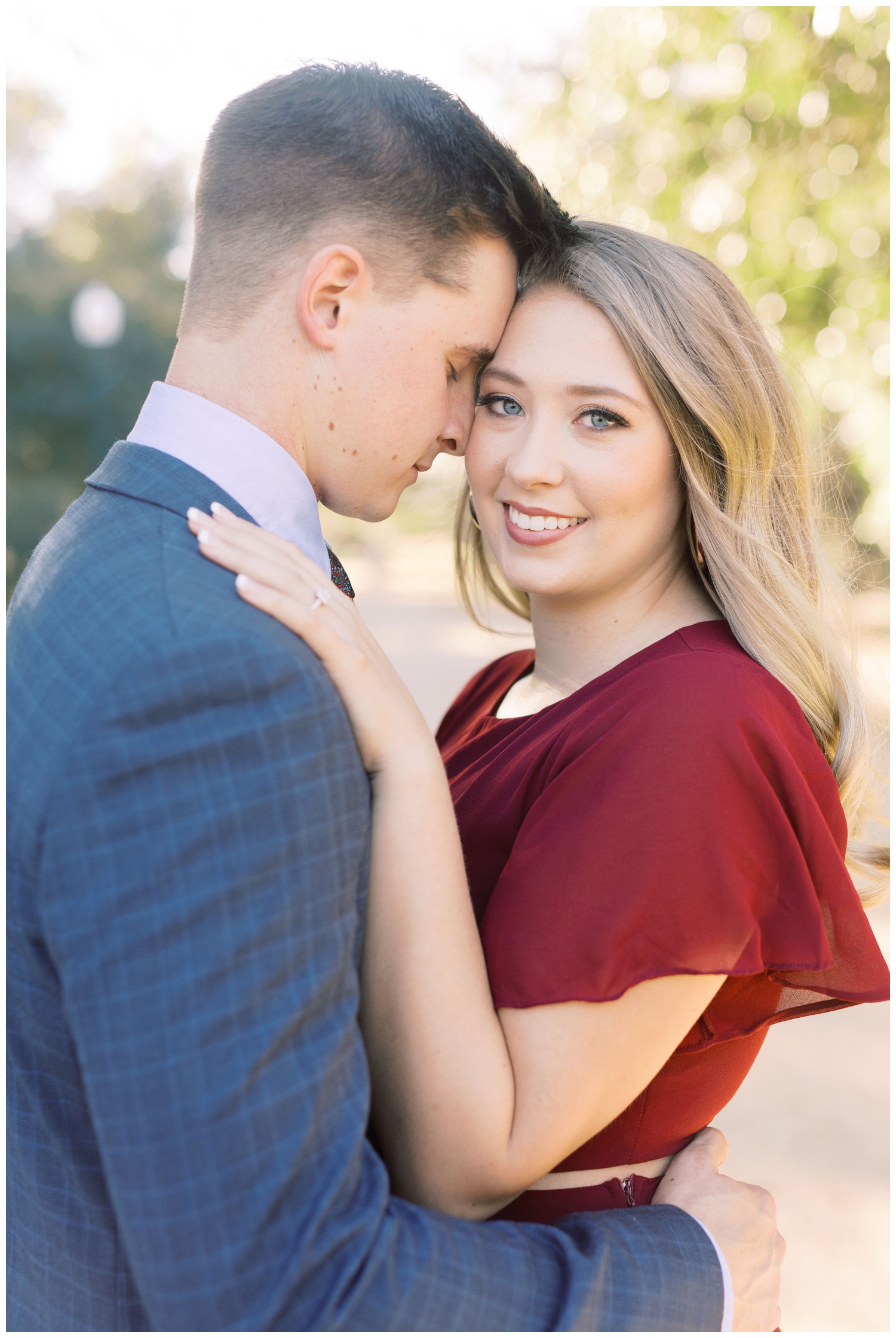 couple portraits with bride wearing burgundy dress and groom in blue suit at Hermann Park