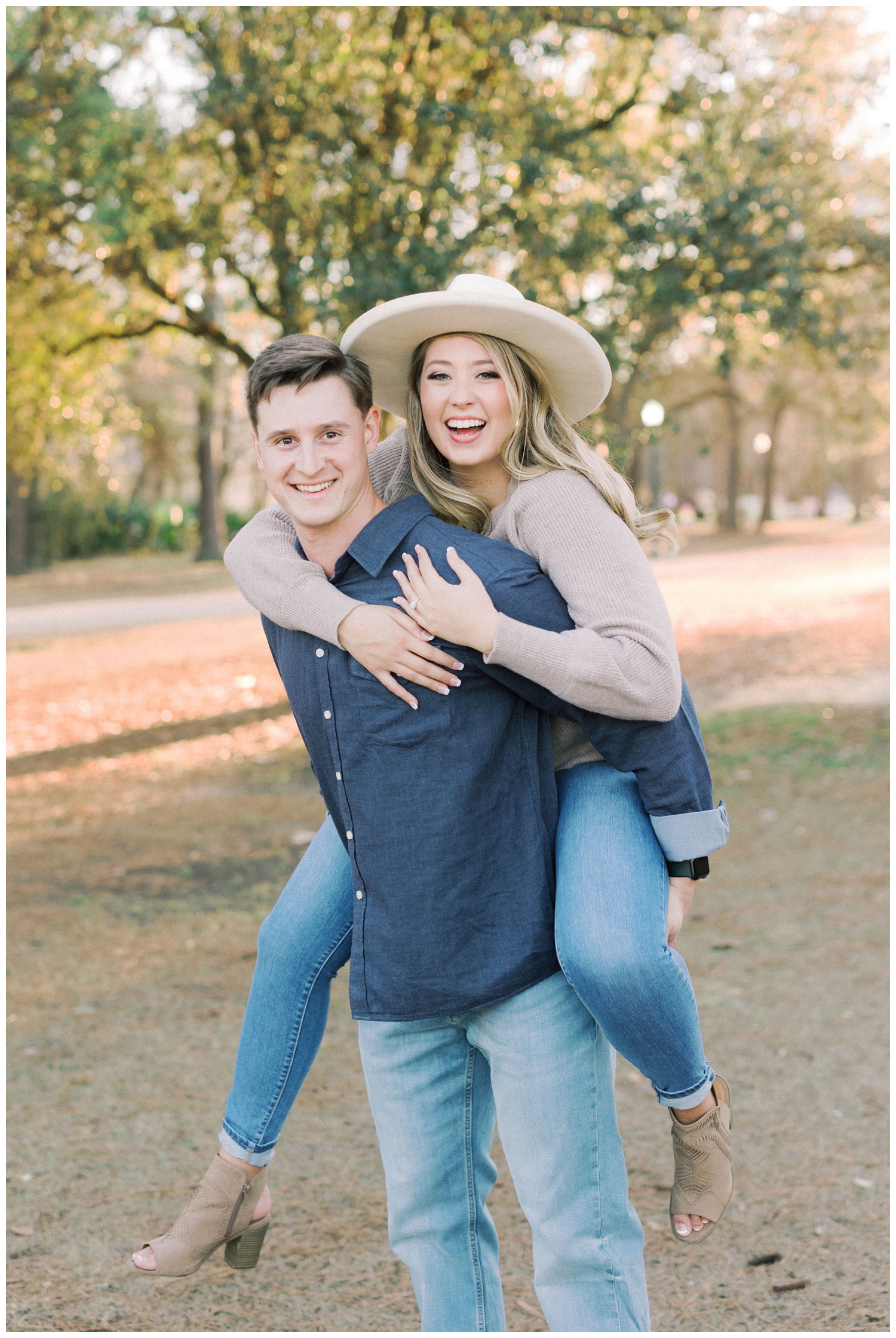 couple on piggyback with denim jeans and cowgirl hat at Hermann Park