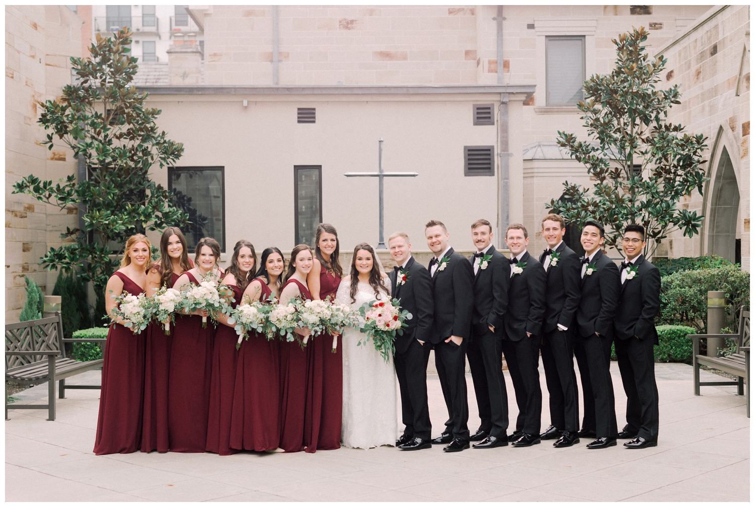 bridal party portrait in wine dresses and black tuxes at Holy Rosary Church