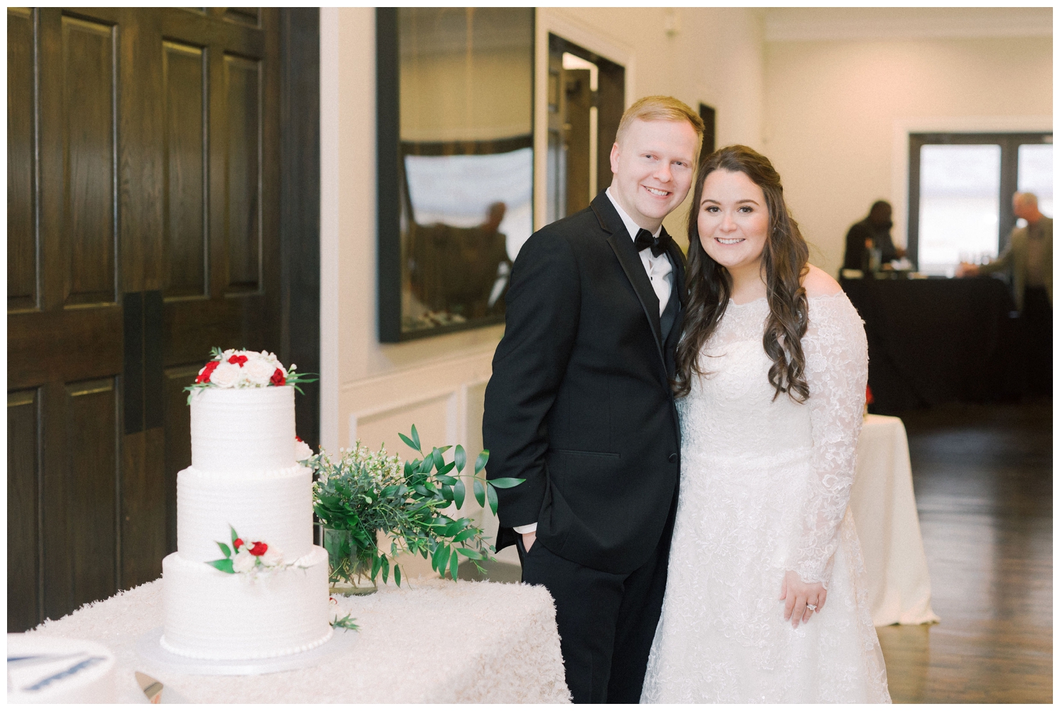 bride and groom with white cake and burgundy florals