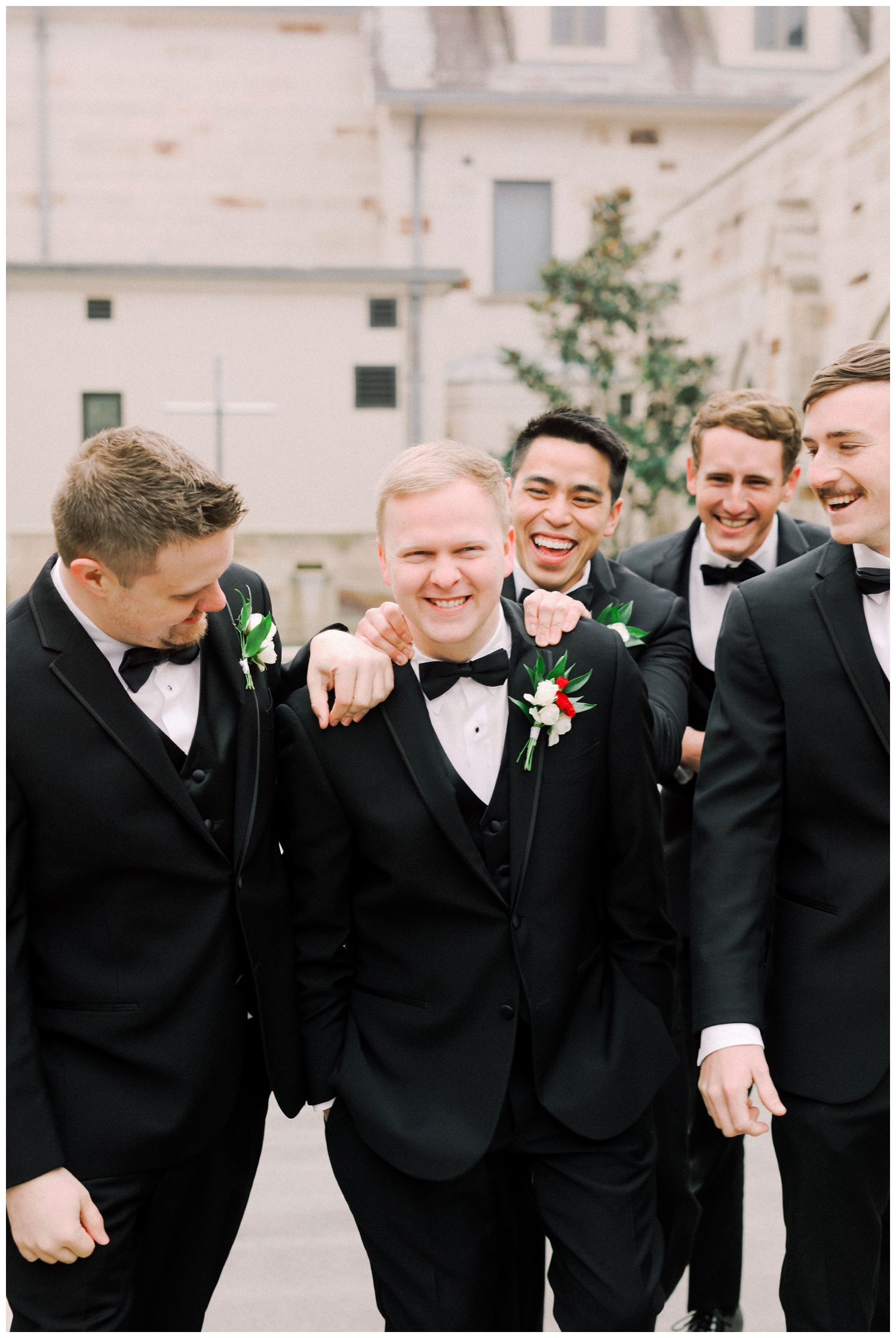 grooms in black tuxedos standing outside Holy Rosary Church