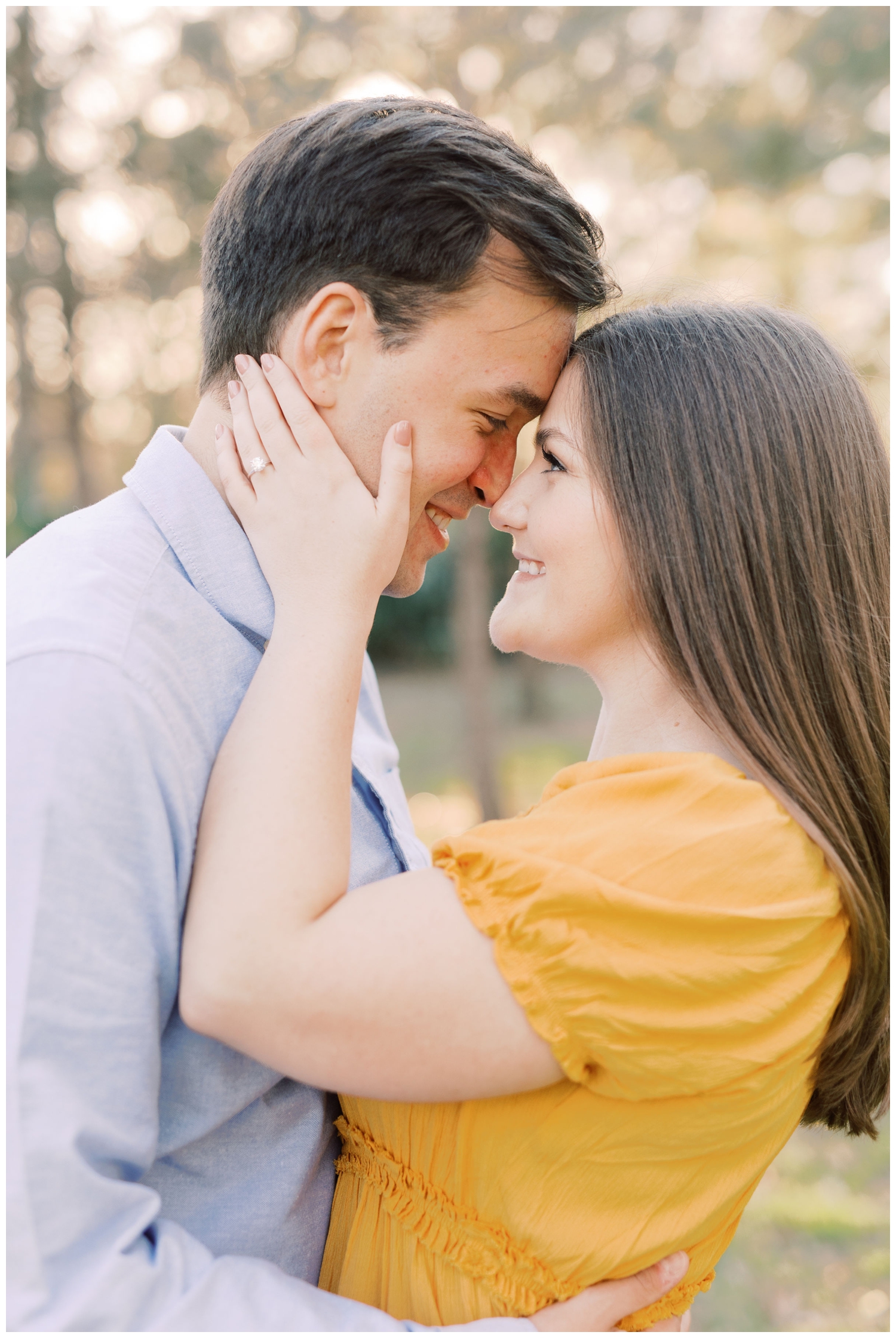 engaged couple in gold dress and blue shirt nose to nose posing for Houston Engagement Photographer