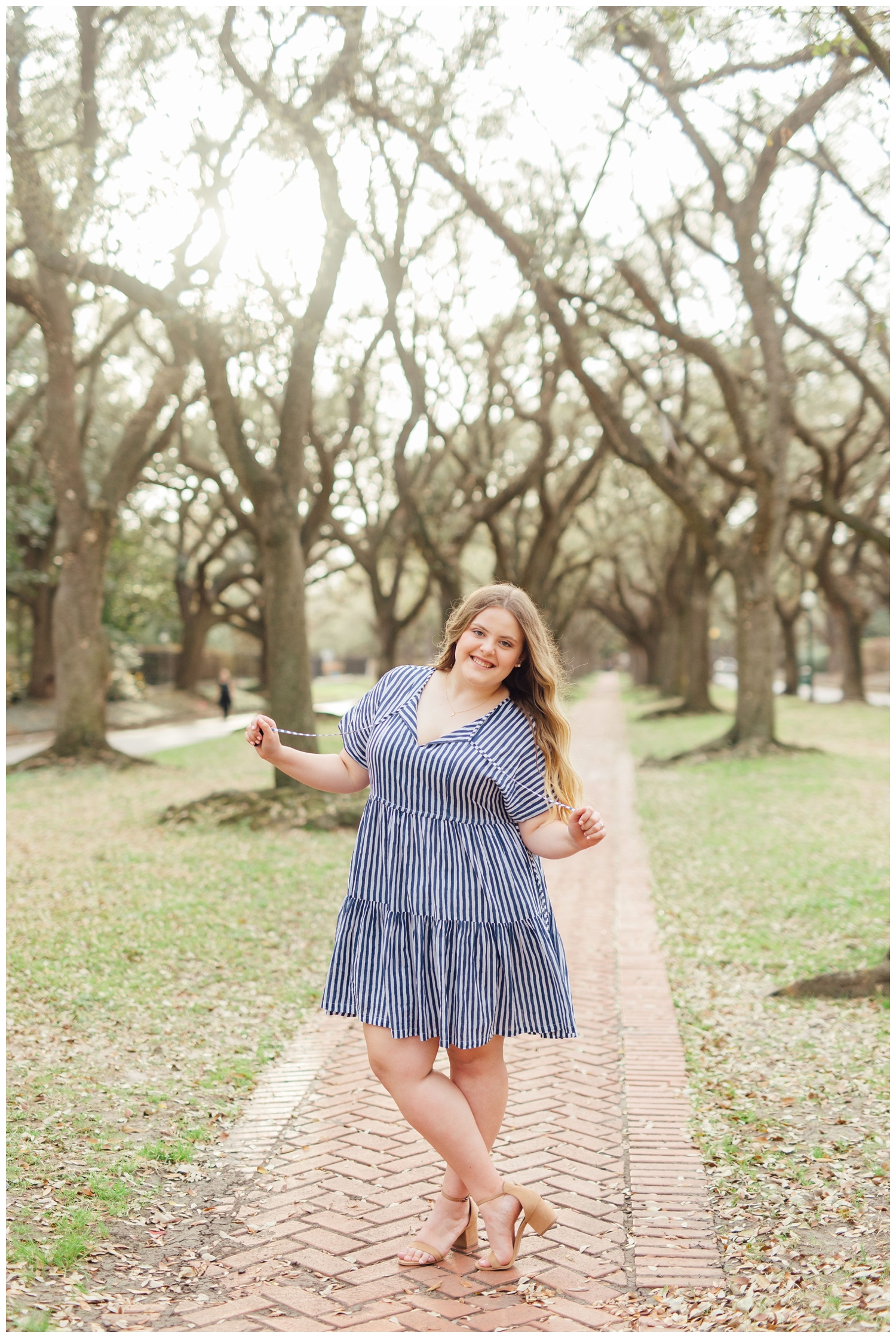 girl twirling hair in blue dress on sidewalk during senior photos downtown Houston