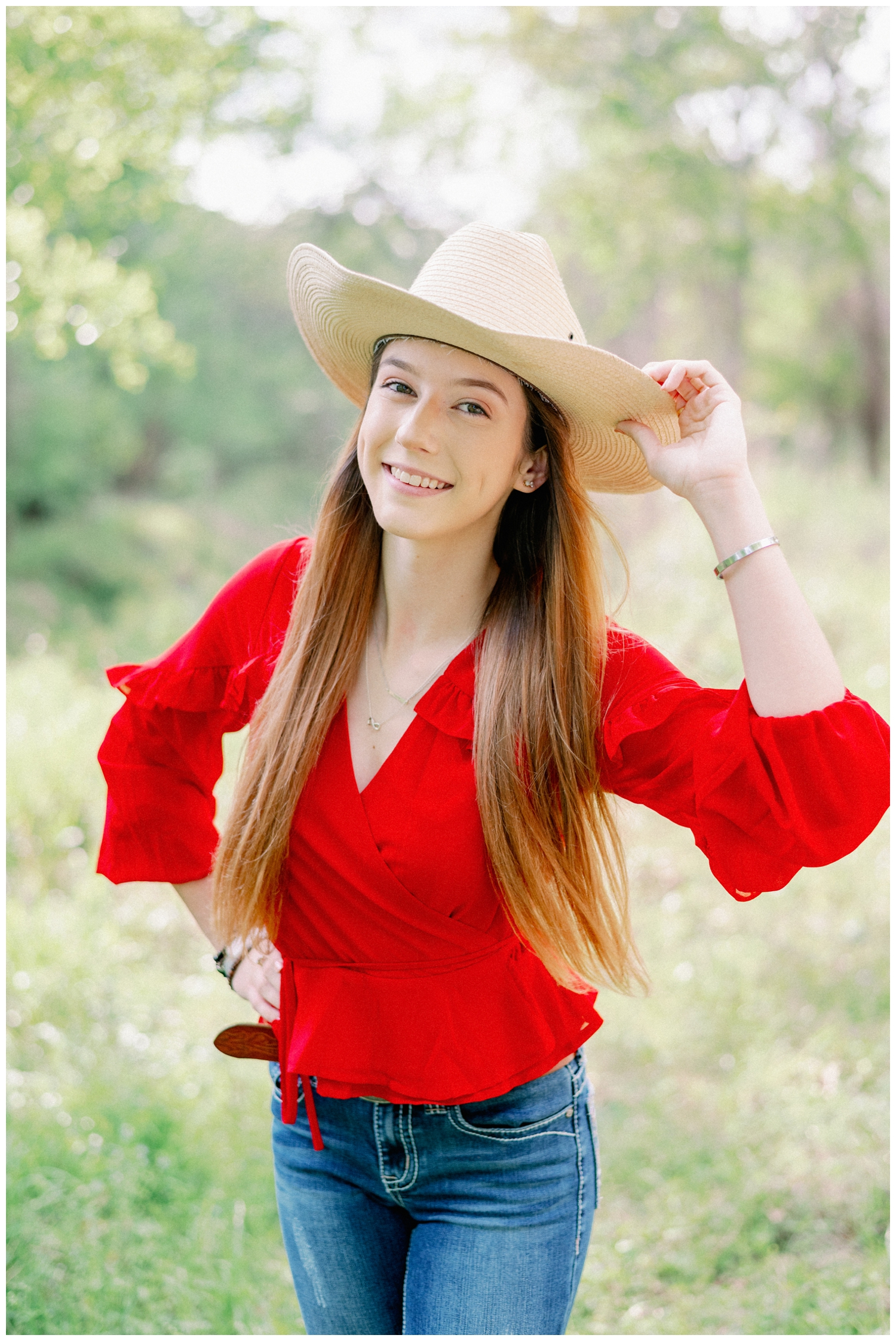 girl tipping her hat in a field for a Cypress senior photographer at Cy-Hope