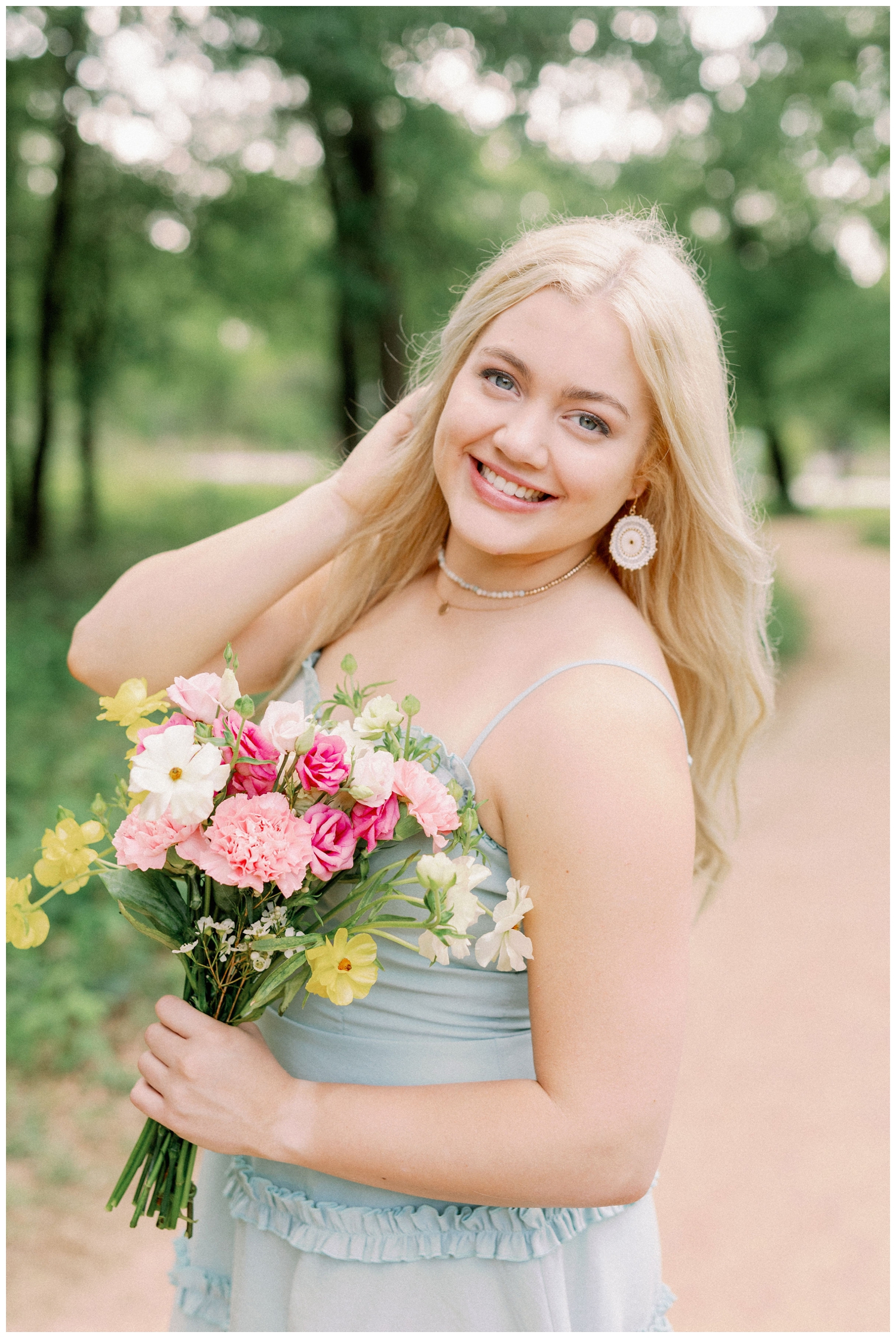 girl posing with hand in hair holding flowers at Houston Arboretum Senior Portraits
