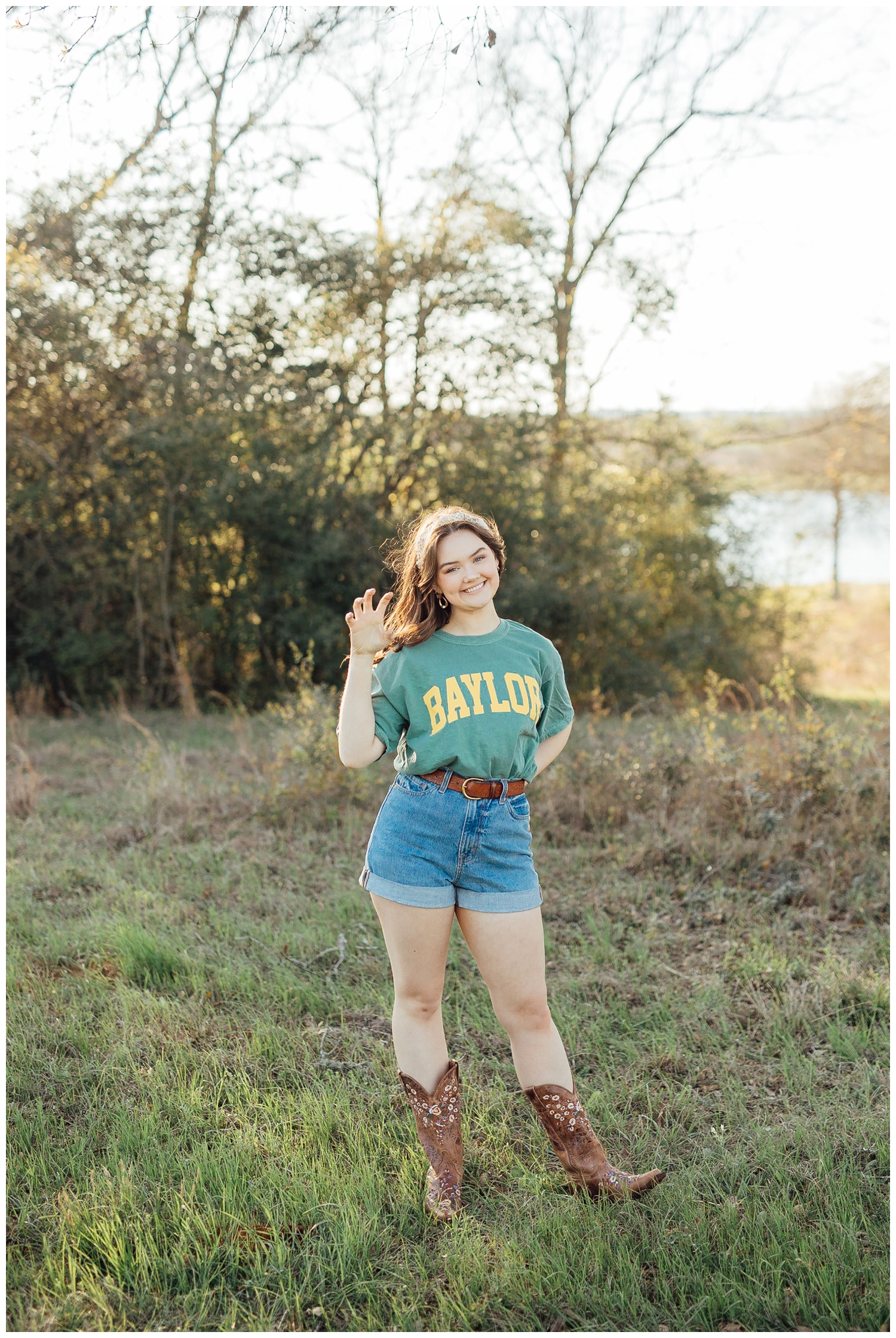 senior girl posing in college tshirt and cowboy boots in a field