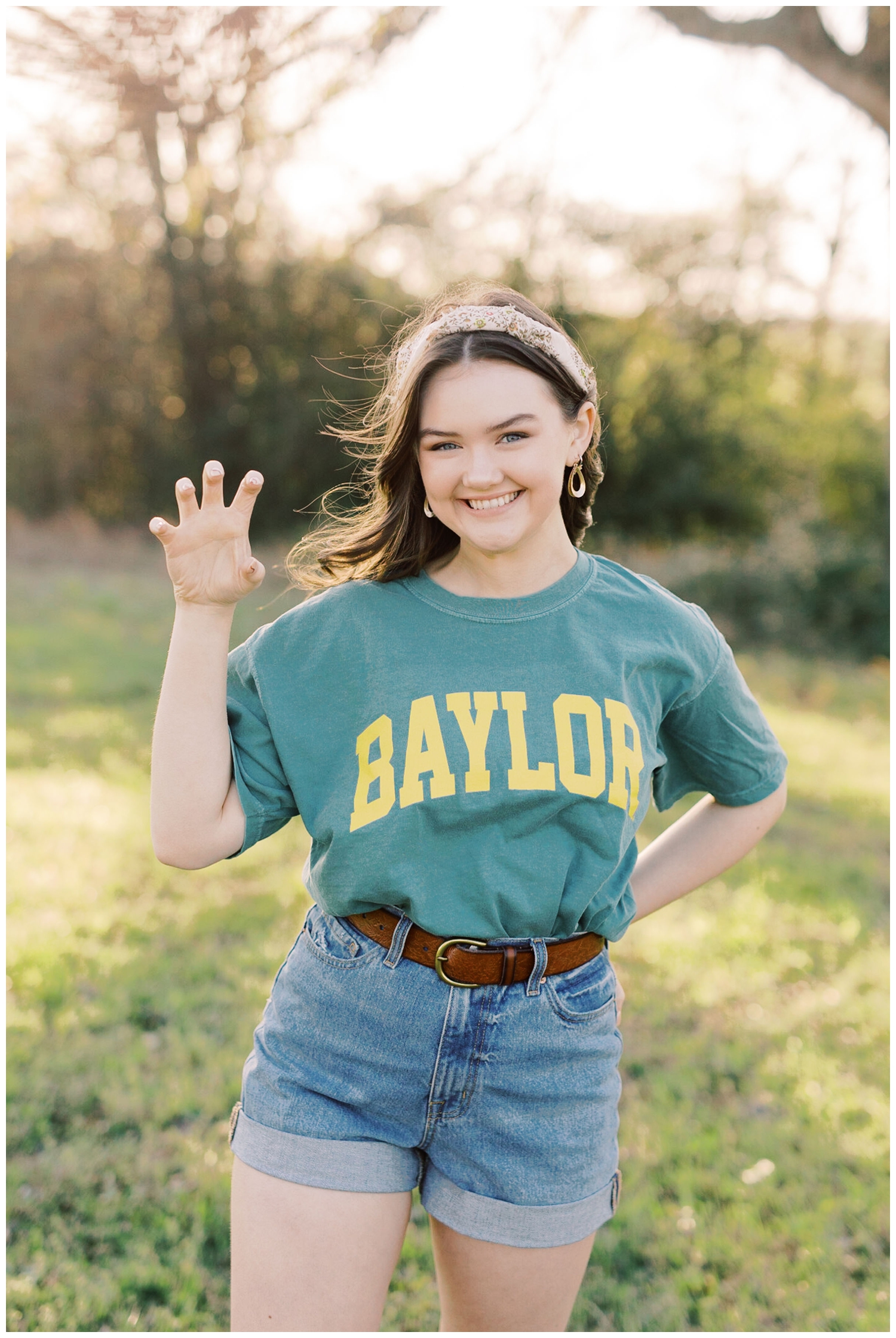 high school senior in Baylor University shirt posing for a Houston outdoor senior photographer