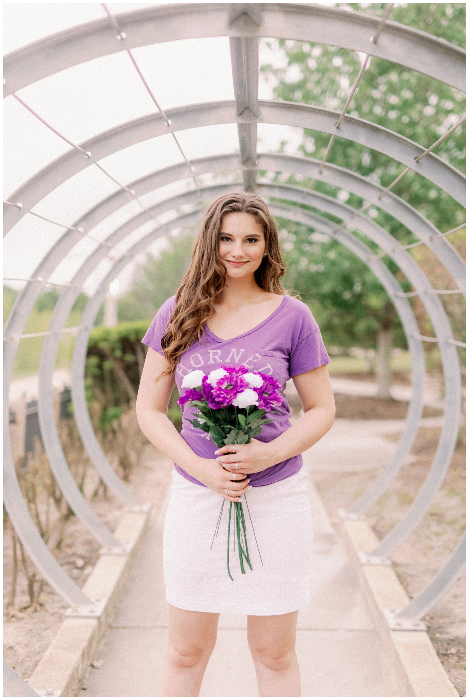 senior girl holding purple and white flowers