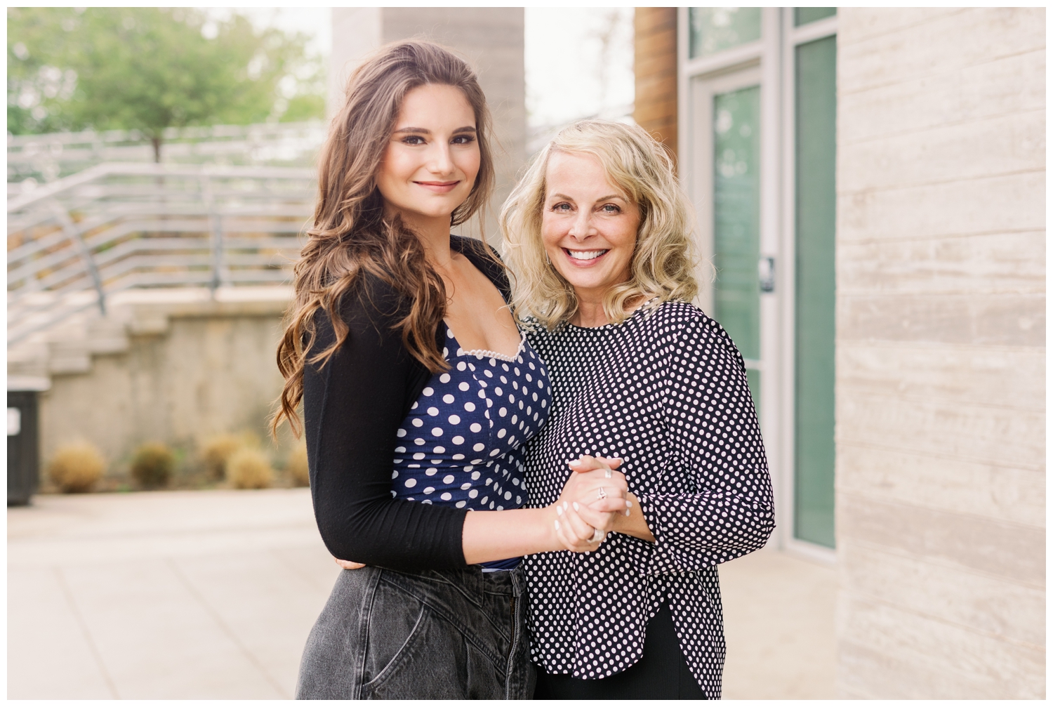 mom and daughter holding hands posing for a senior photographer downtown Houston