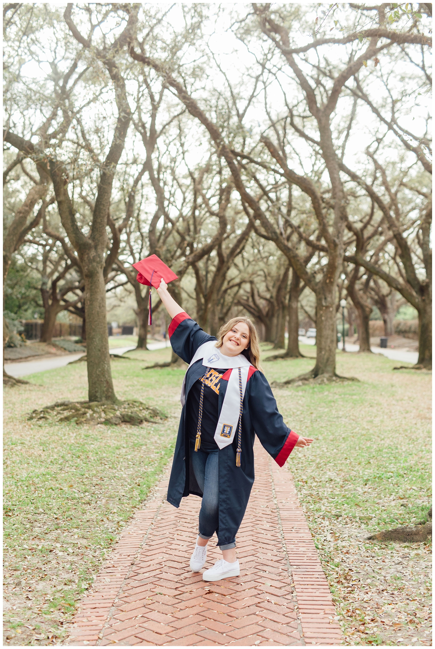 senior girl holding graduation cap in treeline at senior photos downtown Houston
