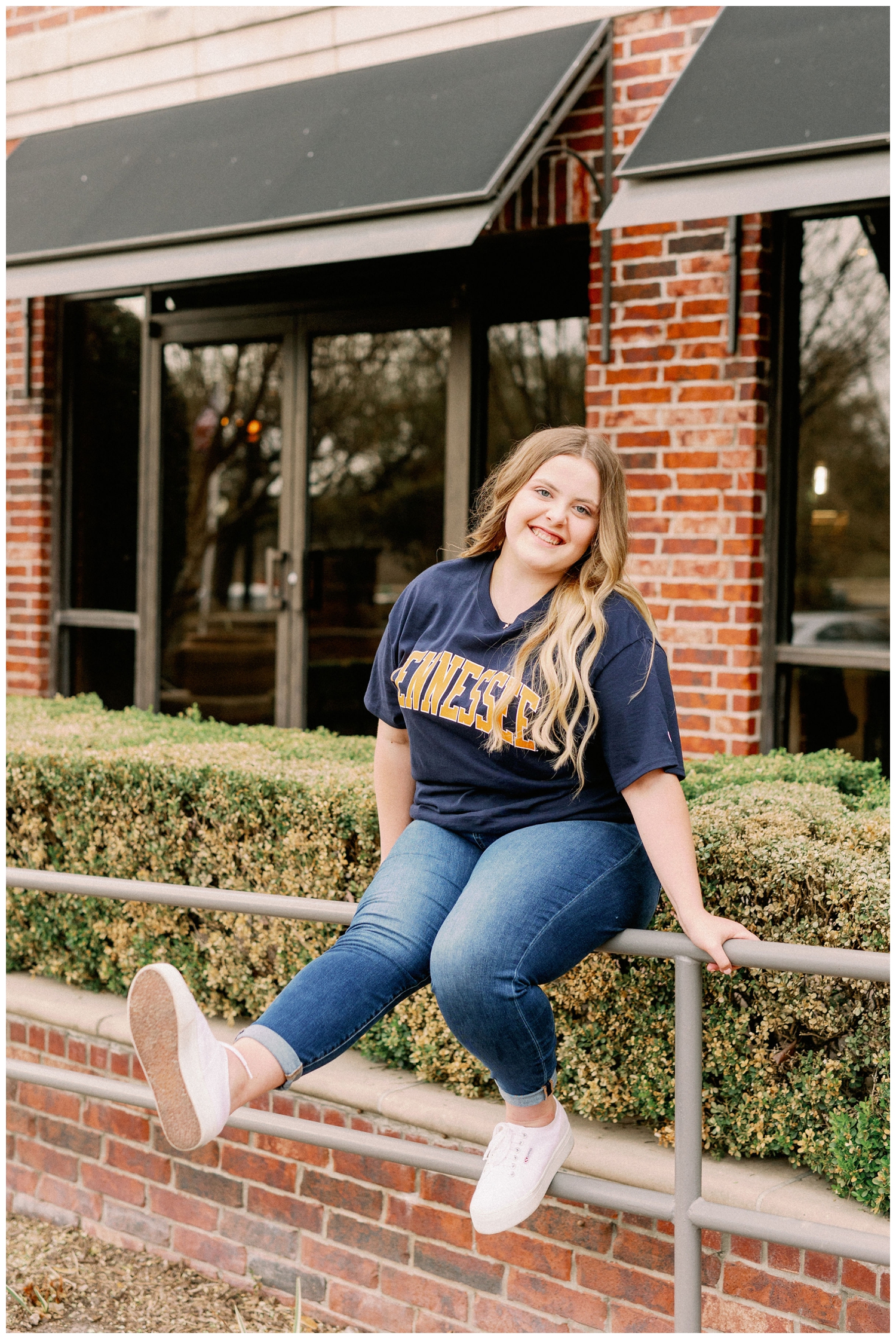 senior girl in a college tshirt sitting on a rail