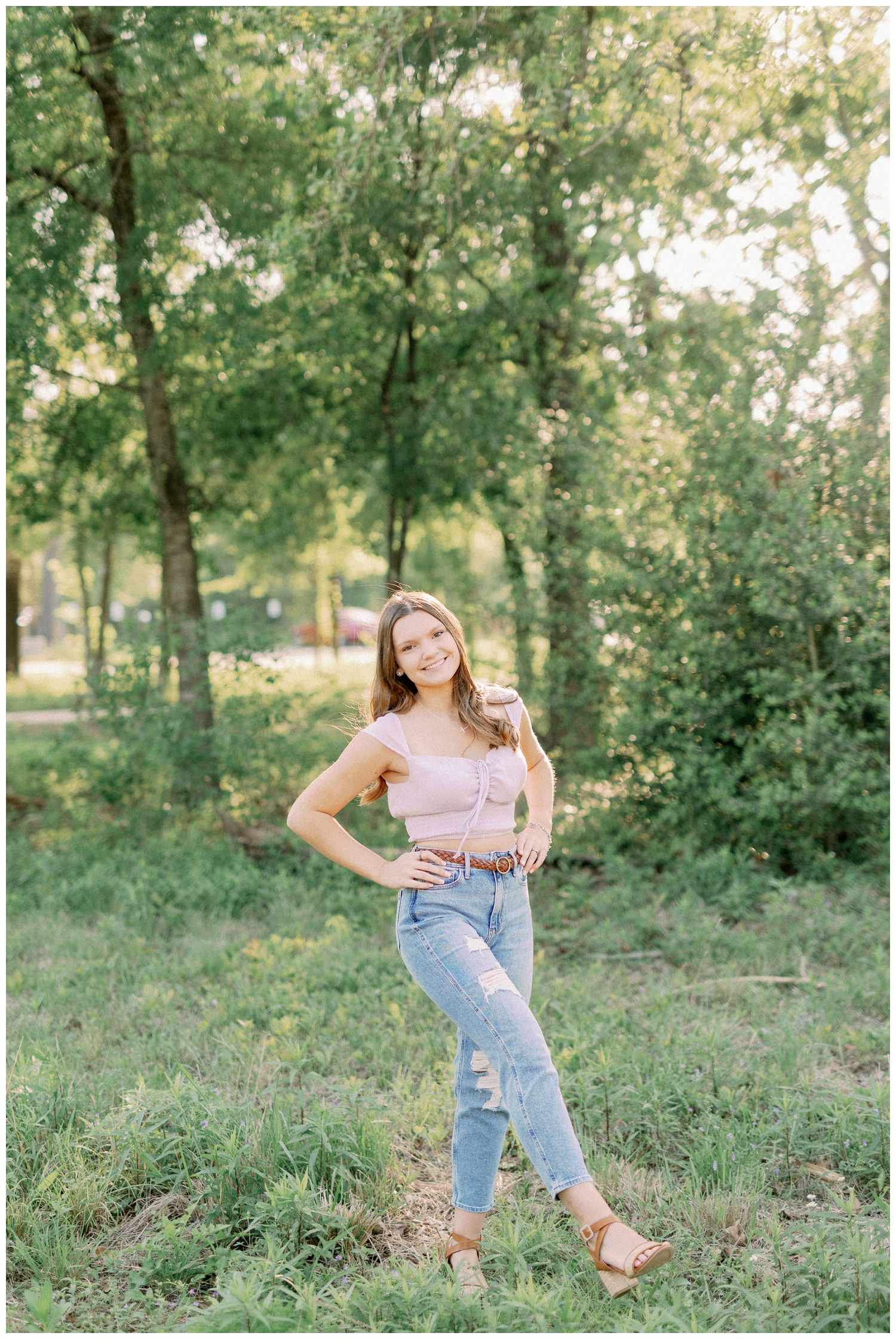 girl standing in a field smiling senior photos Houston Arboretum
