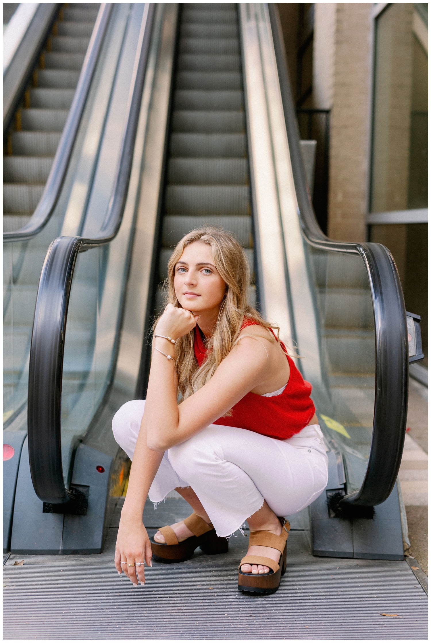 girl kneeling in front of escalator for urban Houston senior photographer