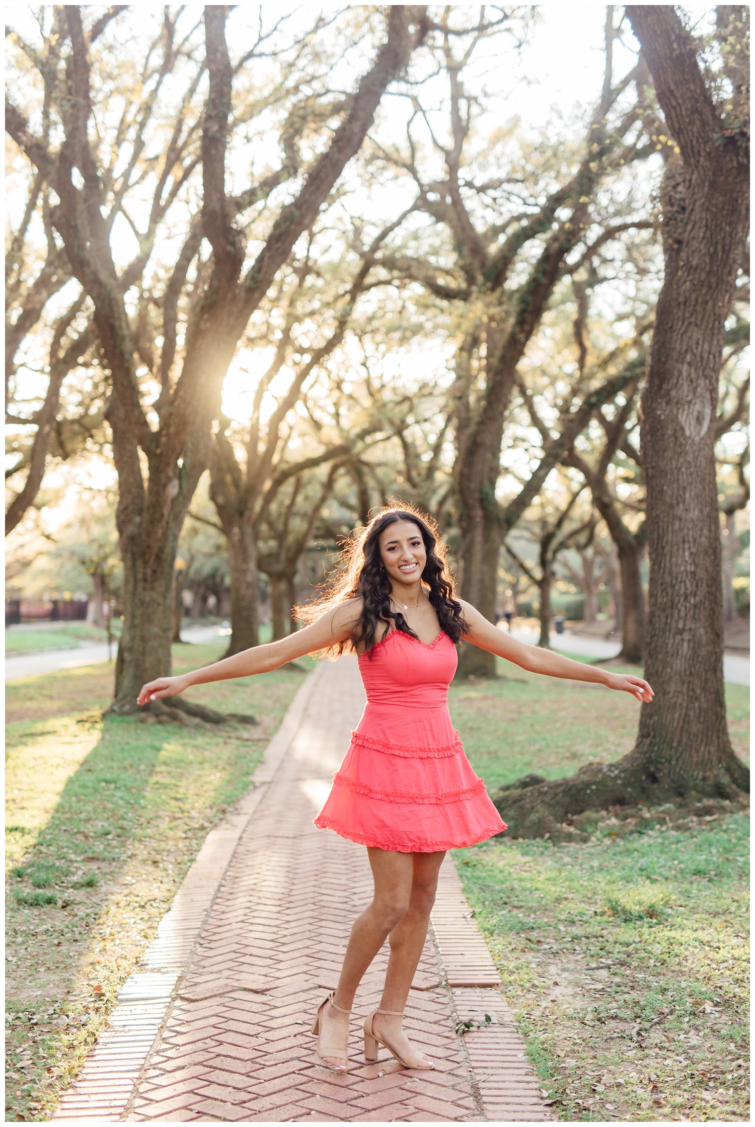 high school senior girl in coral dress spinning for a vibrant Houston senior portraits session