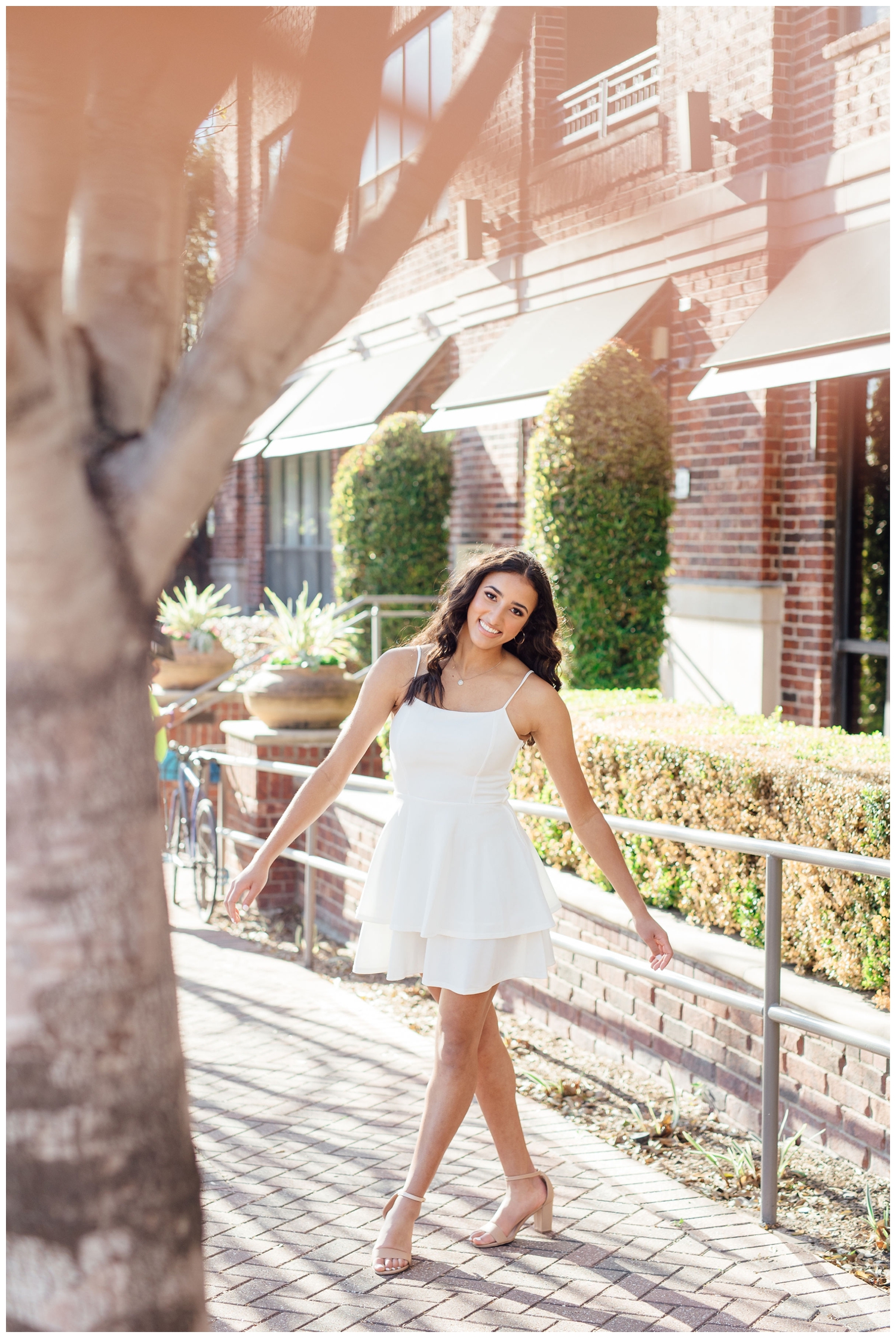 girl twirling in white dress on a sidewalk