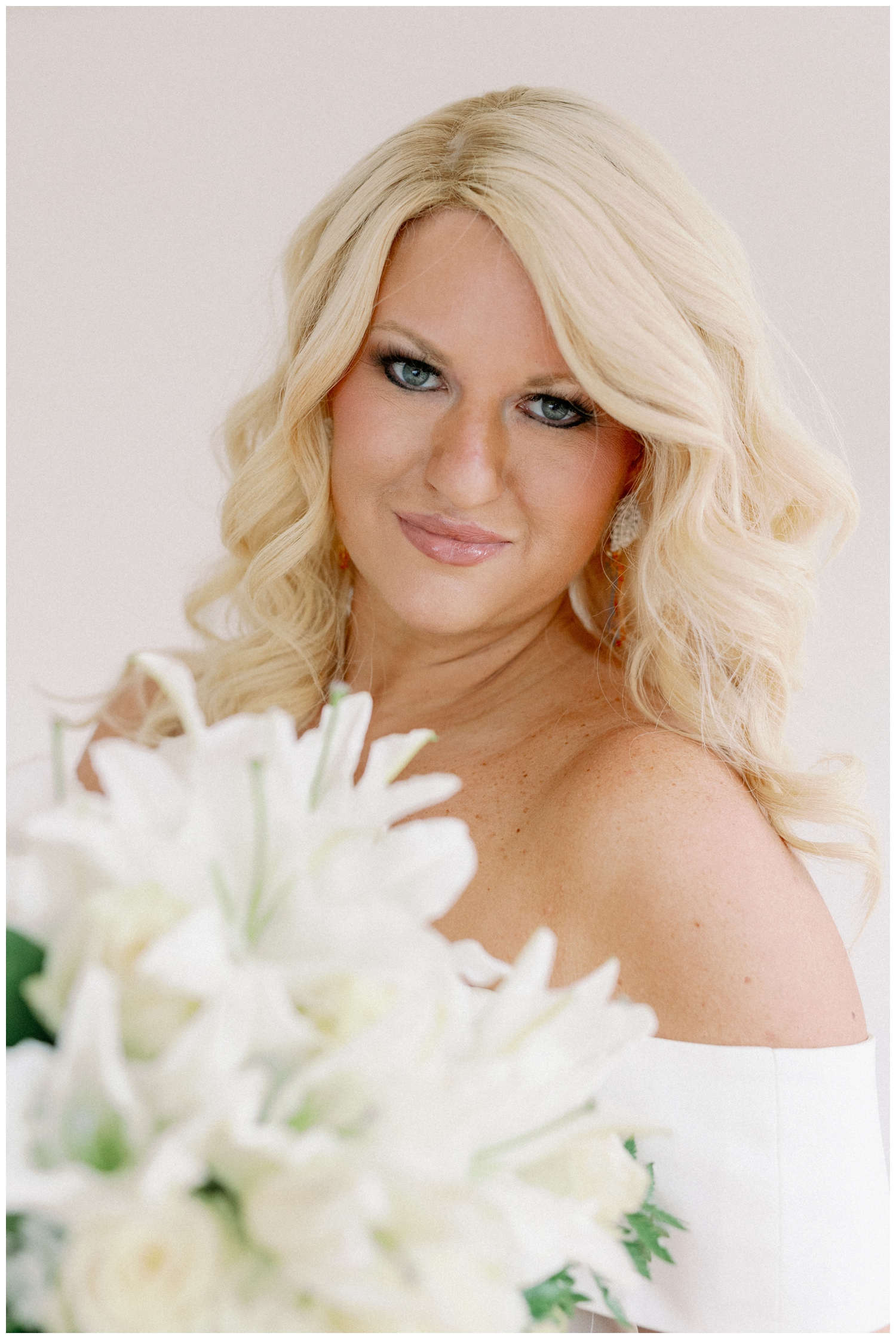 bride smiling at camera with all white floral bouquet
