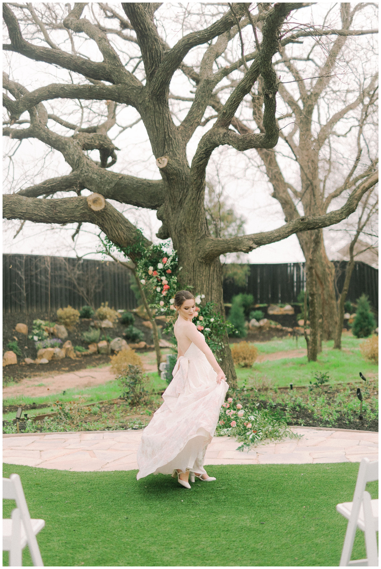 bride twirling pink and white floral wedding dress in the Brighton Abbey Wedding garden by oak tree with floral installation