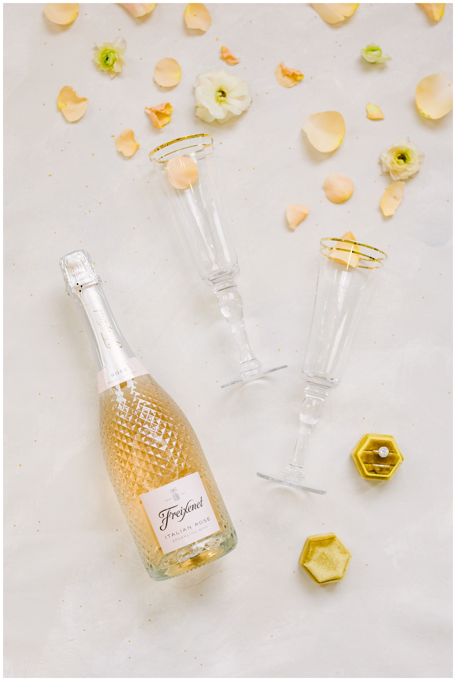 bottle of rose wine with champagne flutes and flowers