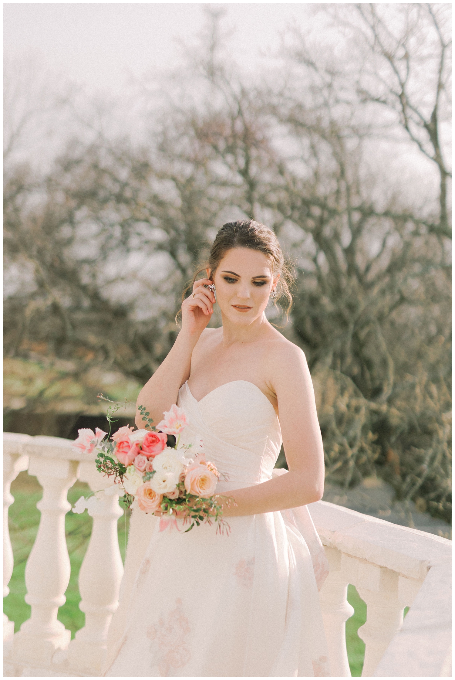 bride posing on balcony at Brighton Abbey holding pink and white bouquet