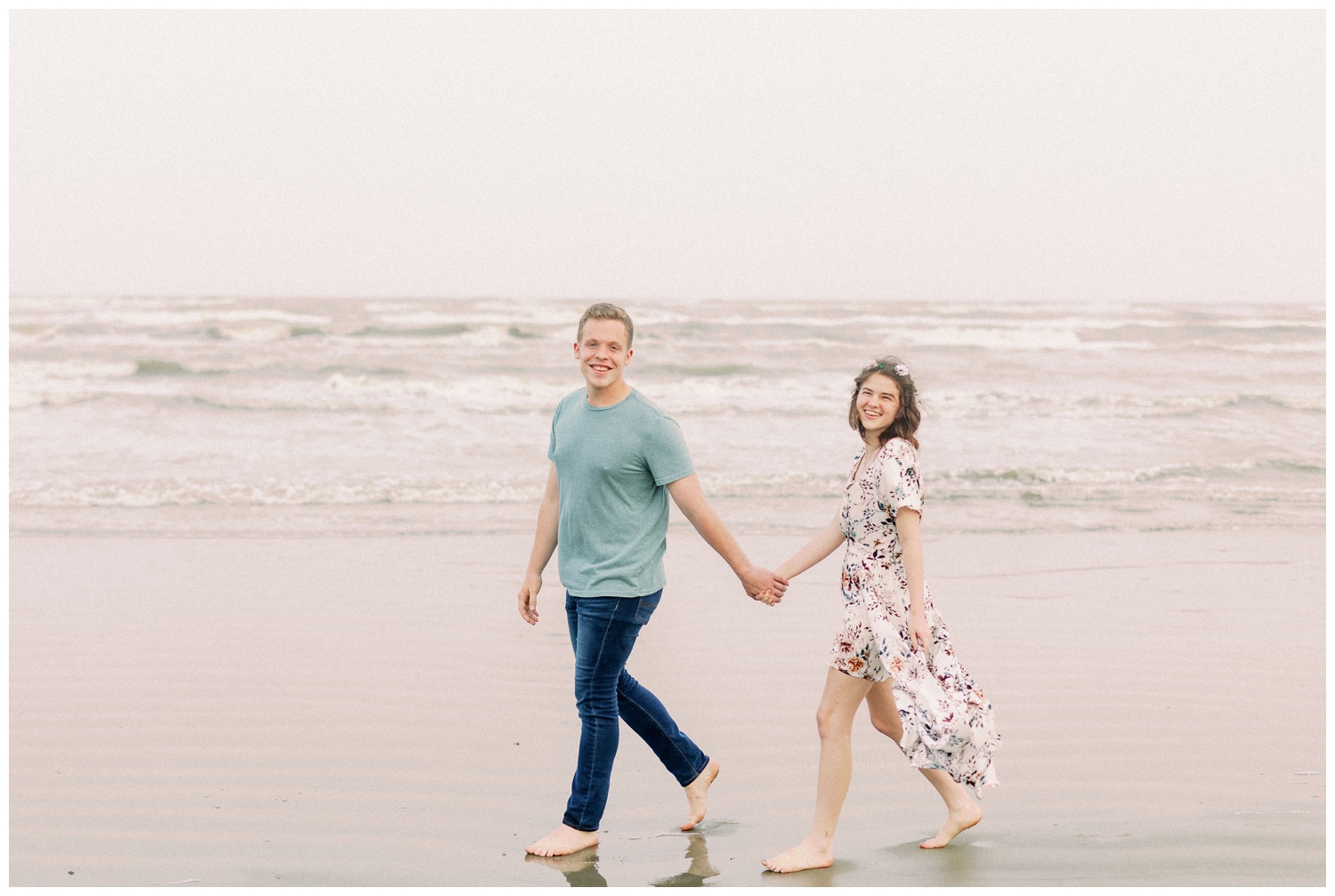 couple holding hands walking on Galveston Beach engagement session