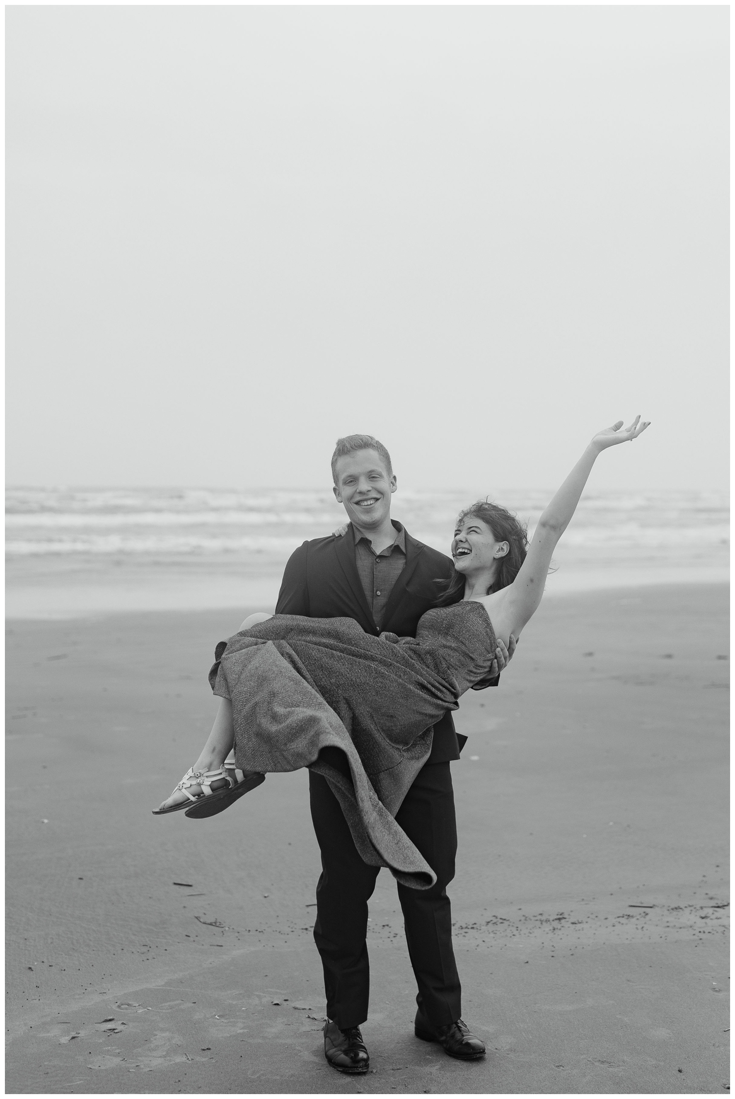 black and white photo of groom holding bride on the beach