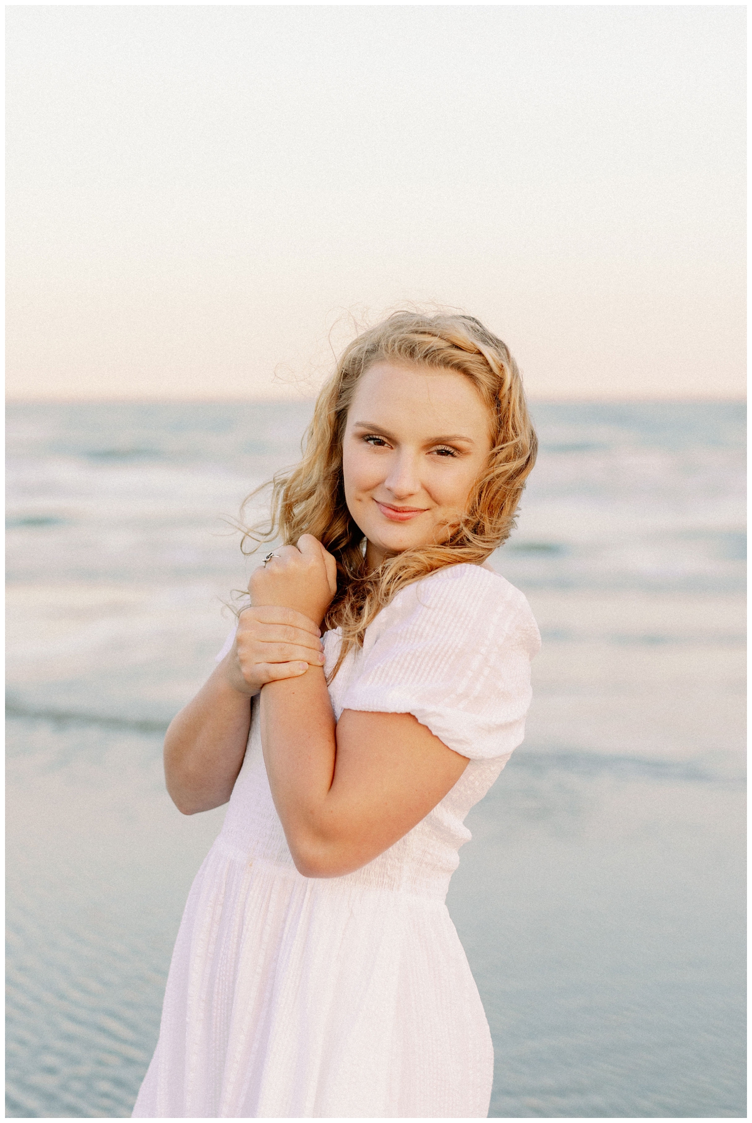 girl holding hands while posing Galveston beach senior pictures