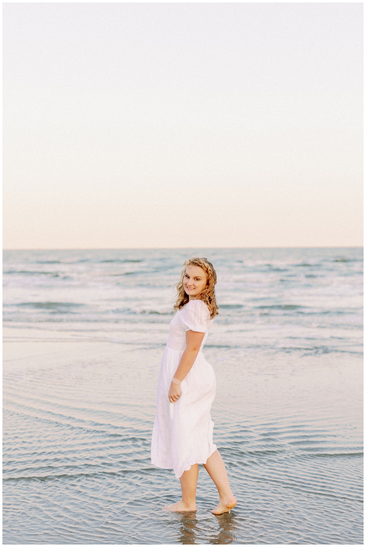 girl in white dress twirling dress on beach in Galveston, Texas