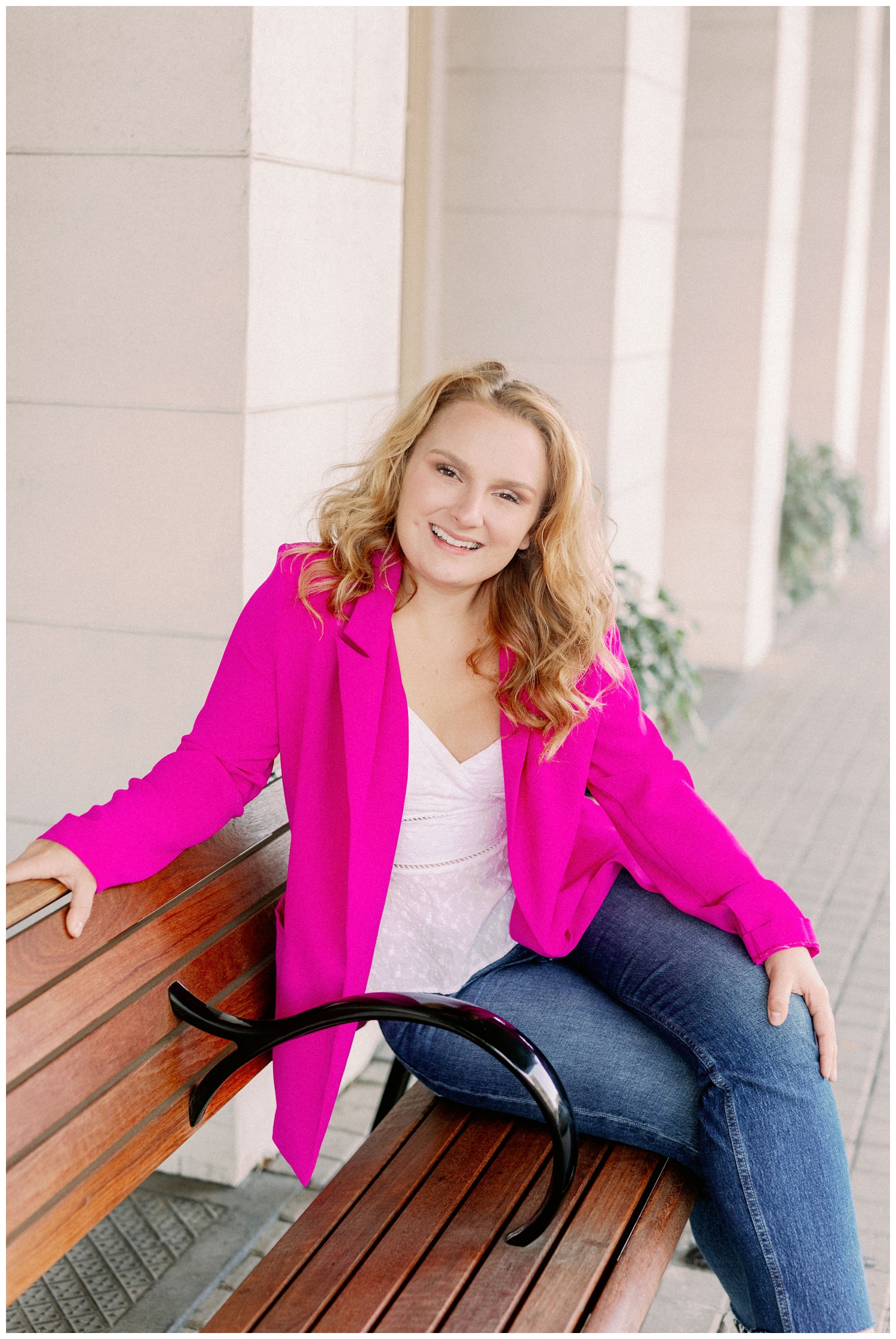 girl in hot pink jacket and jeans sitting on a beach in Galveston, Texas