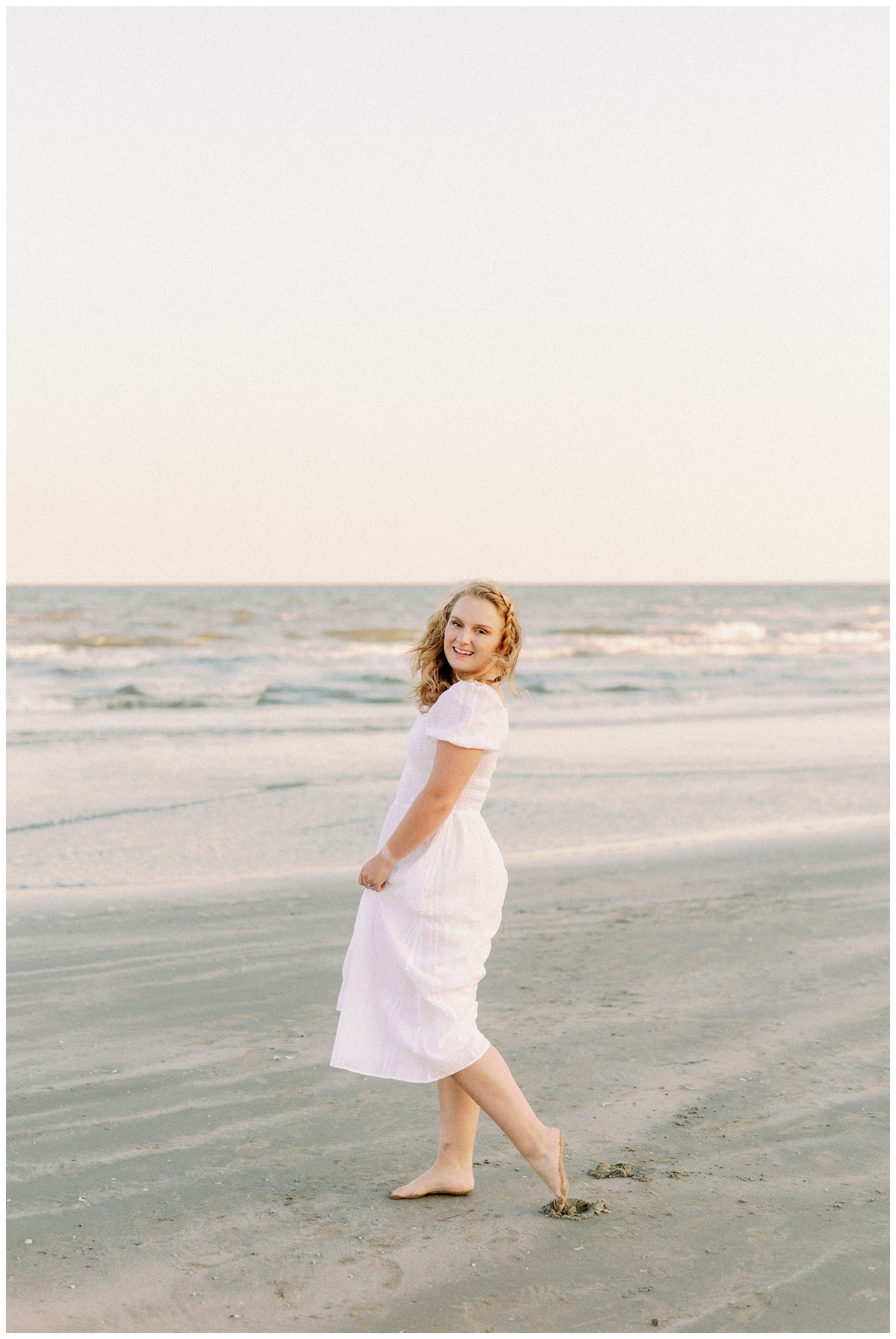 girl in white dress twirling dress on Galveston Beach