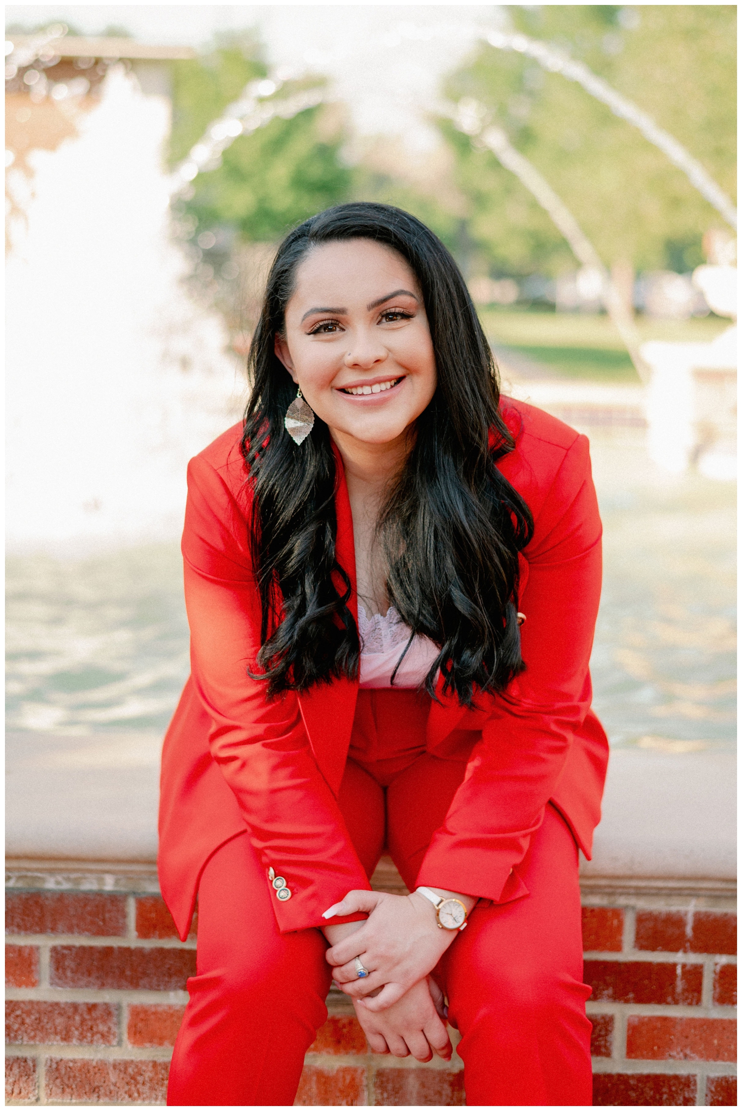 girl smiling in a red suit sitting in front of a fountain in Houston, Texas
