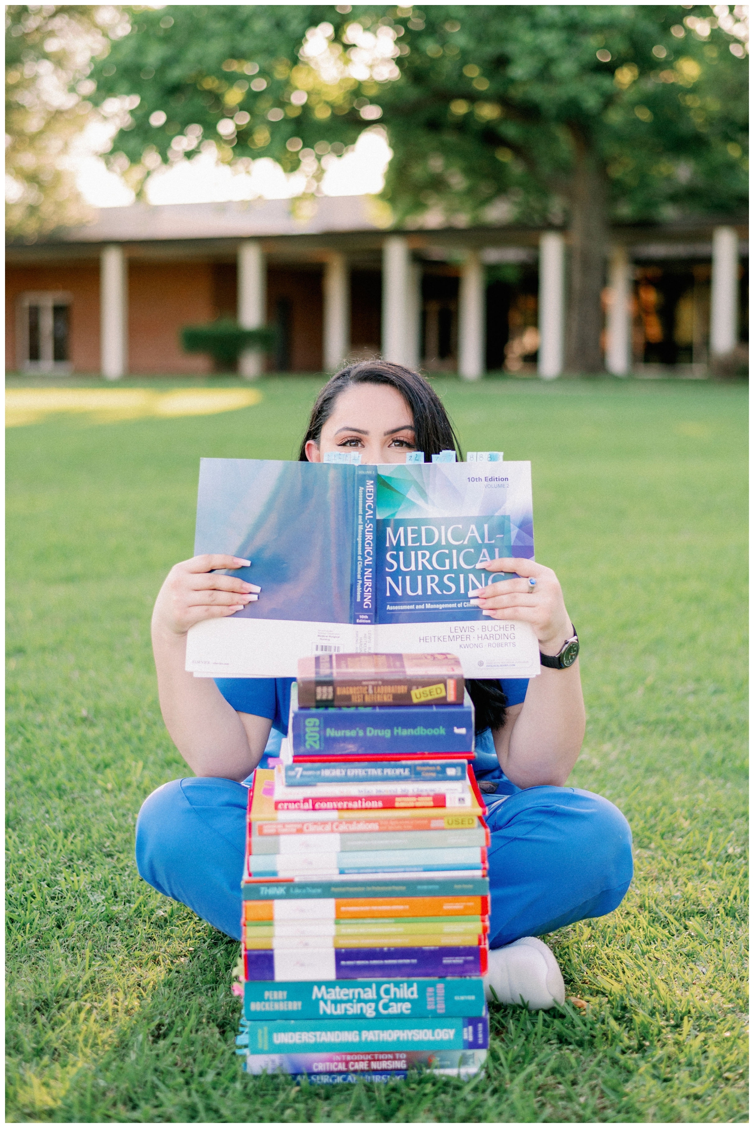 girl on the lawn at Houston Baptist University with a stack of nursing books