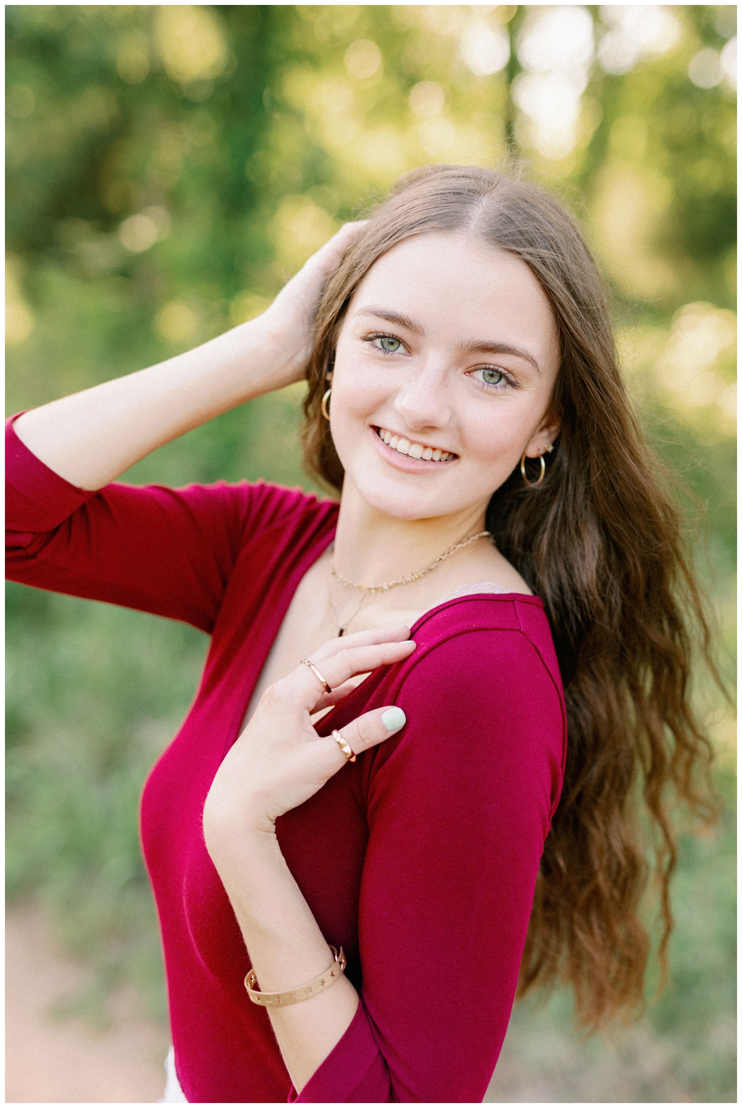 Houston garden senior session with girl in burgundy top smiling at camera