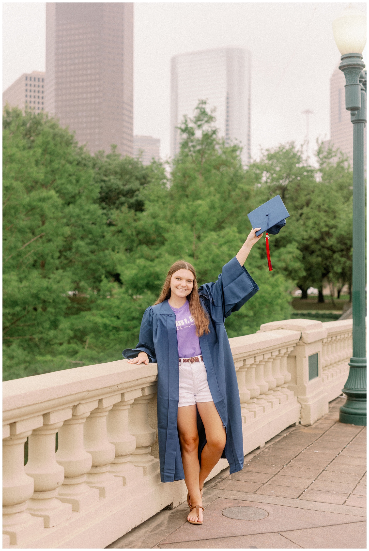 girl standing on Sabine Bridge in downtown Houston in cap and gown for Houston senior model team