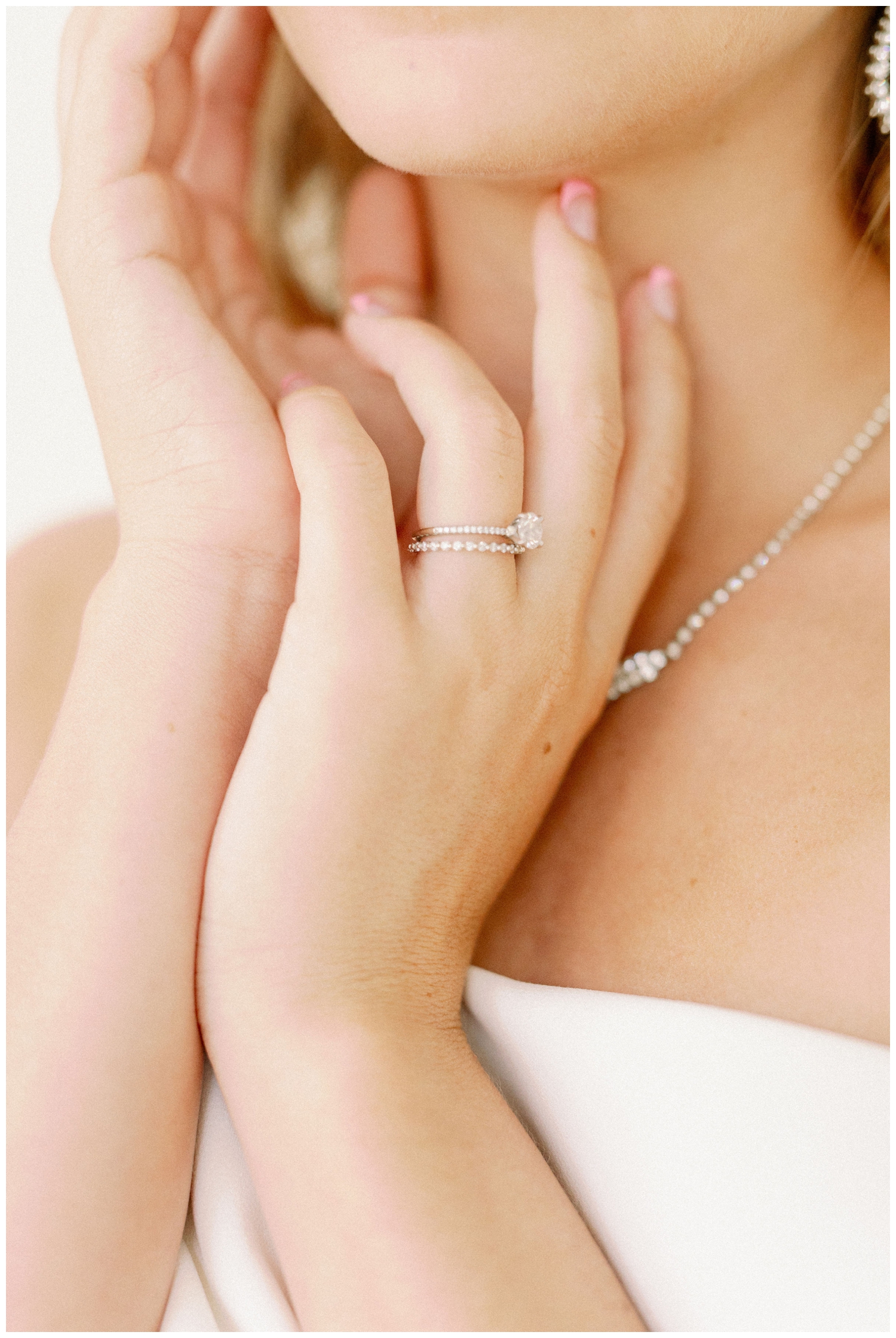 bride's hands clasped together with wedding ring by chin