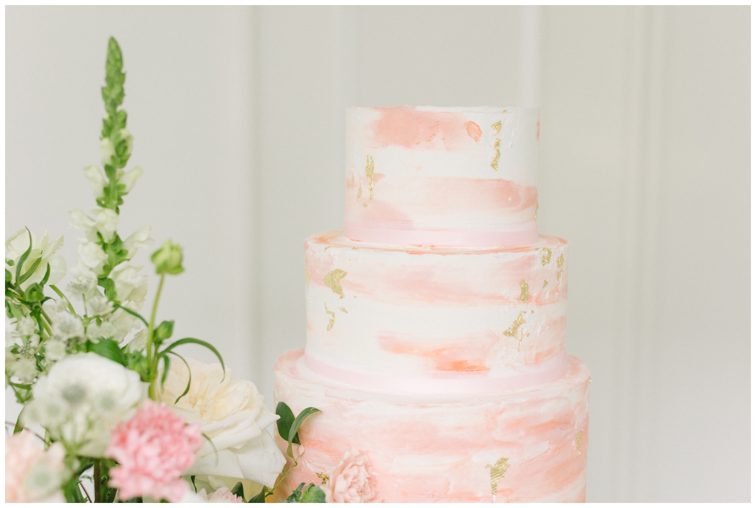 white wedding cake with pink and peach etching