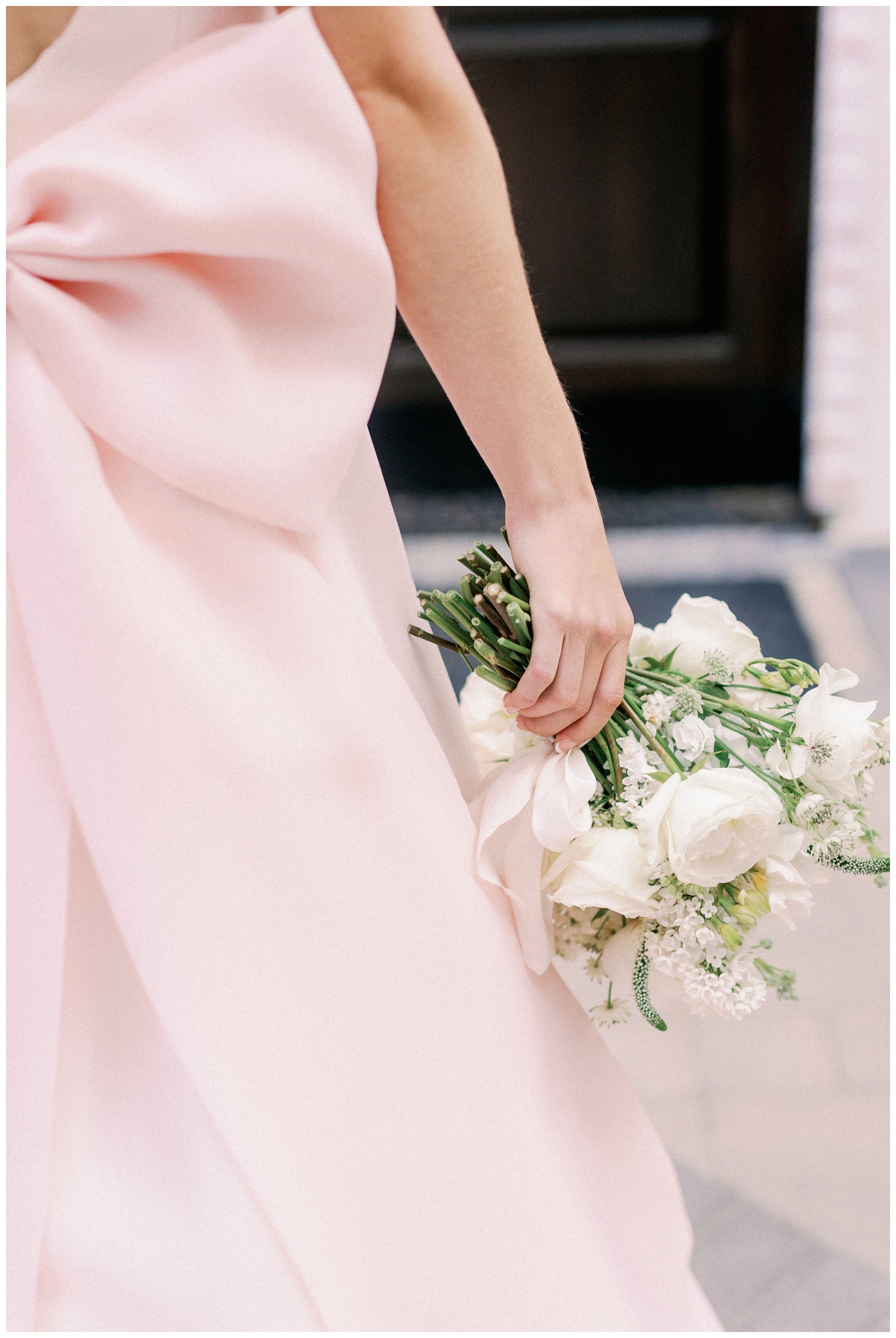 bride in pink wedding gown holding white bouquet down by her side